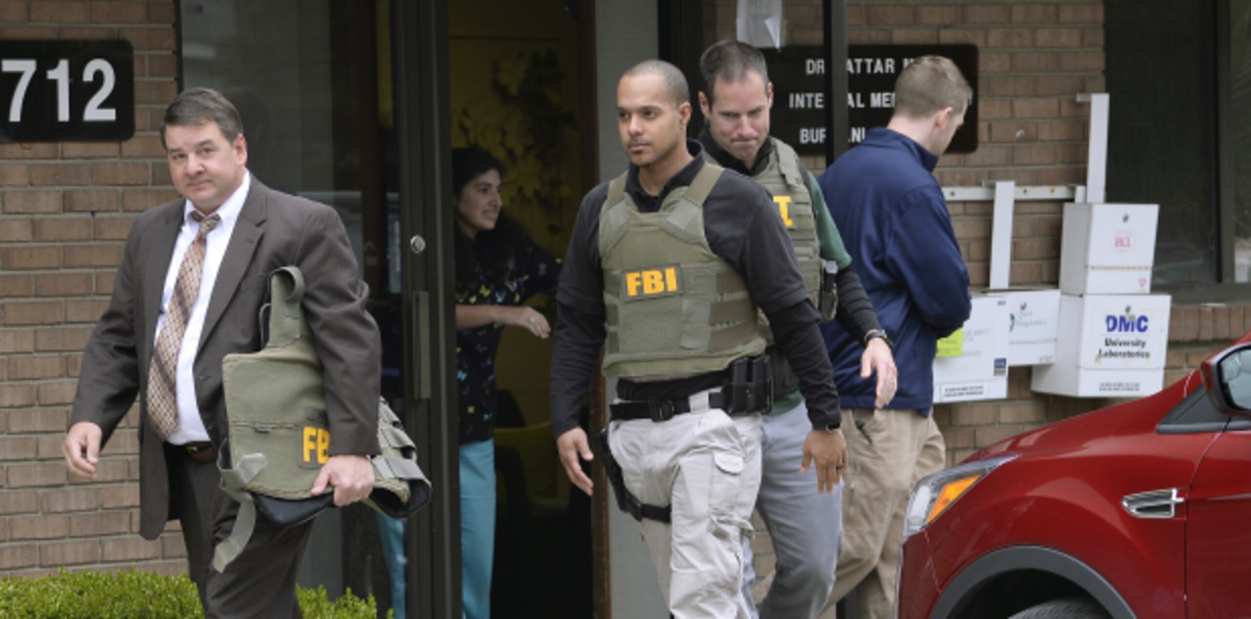 Agentes federales salen de la oficina del doctor Attar en el Burhani Clinic, en Livonia. (AP)