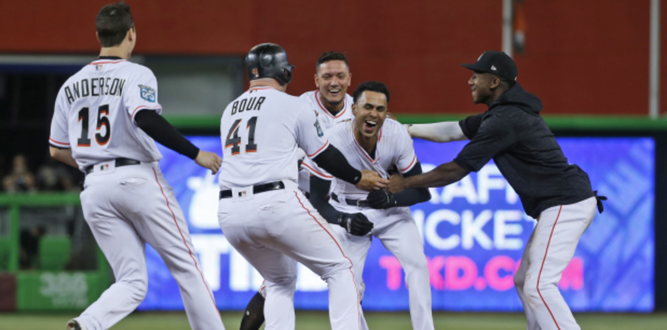 Yadiel Rivera (segundo de derecha a izquierda) es felicitado por sus compañeros de los Marlins de Miami tras conectar un sencillo productor en la décima entrada del encuentro ante los Filis de Filadelfia. (AP)