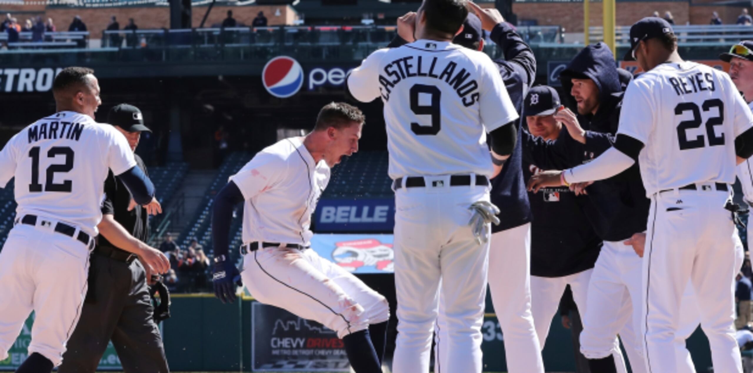 El jugador de los Tigres de Detroit JaCoby Jones, al centro, pisa el plato, en medio de la celebración de sus compañeros tras batear un decisivo jonrón en el décimo episodio en el primer partido de hoy de esta novena contra los Reales de Kansas City. (AP)