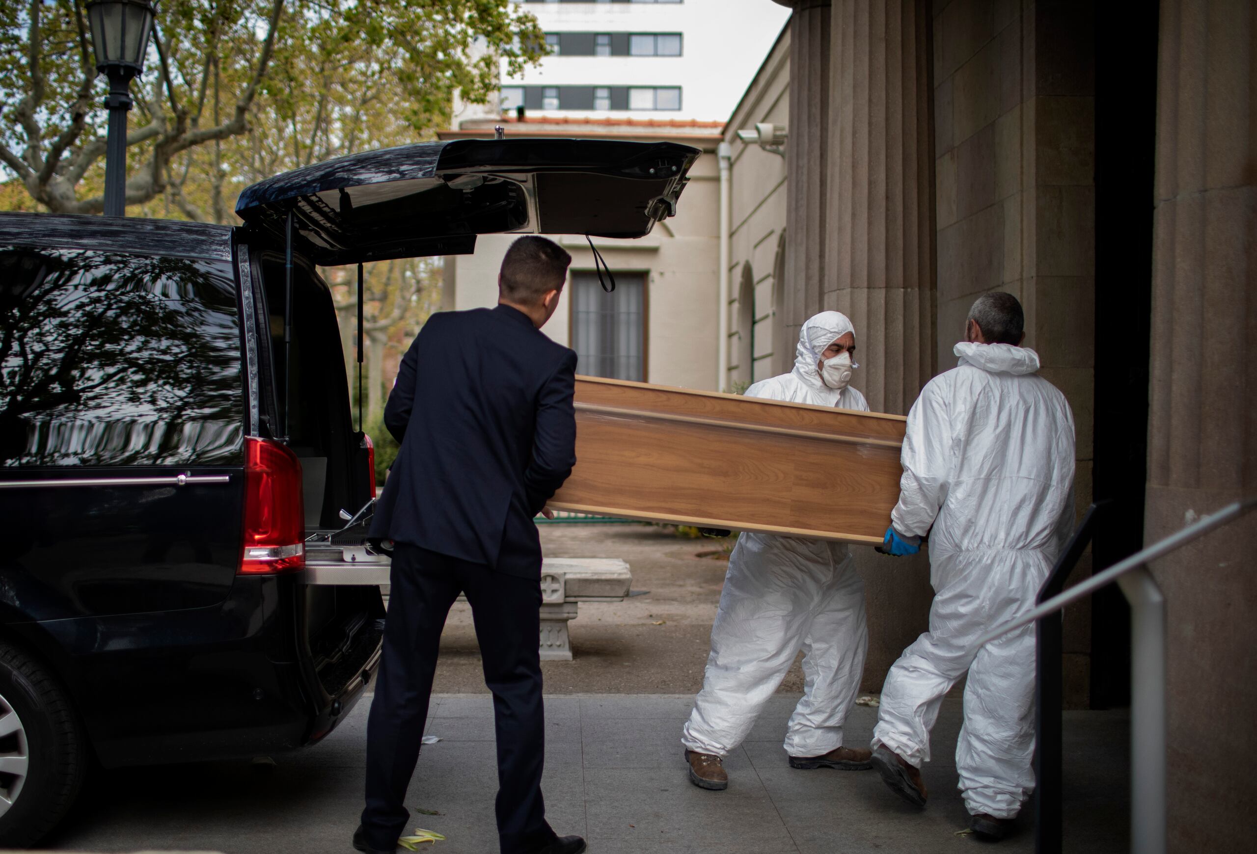 Trabajadores llevan un ataúd para un entierro en Barcelona durante el brote de coronavirus.