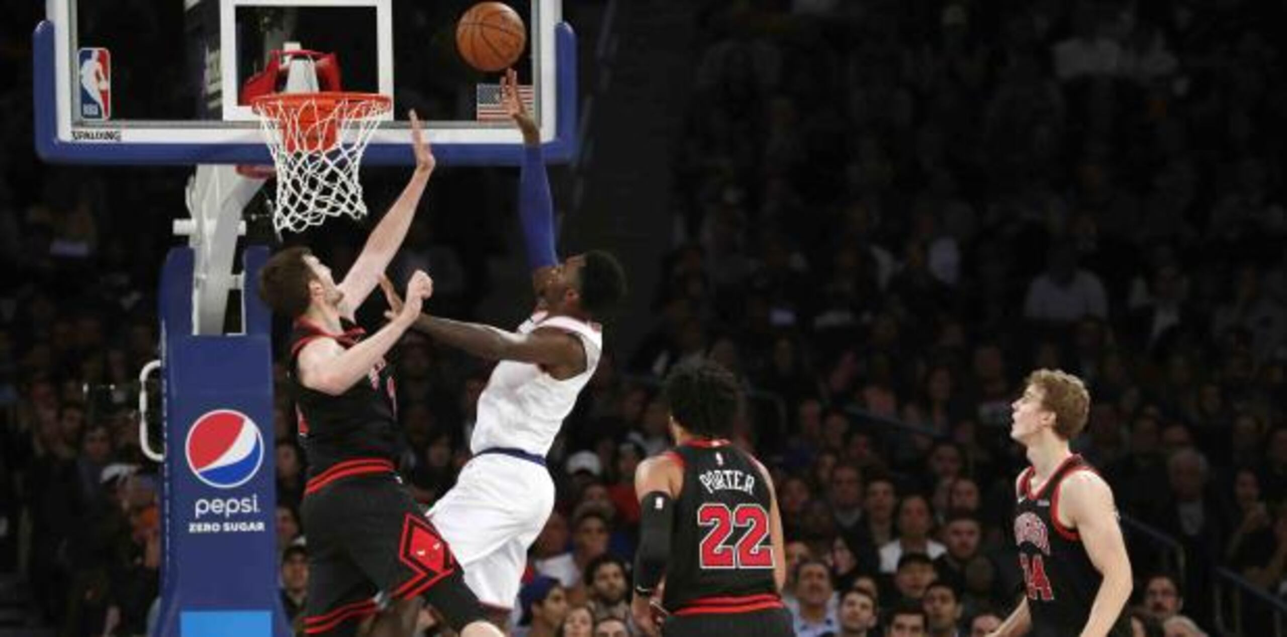 Bobby Portis, en uniforme blanco, de los Knicks, se levanta para colar dos de los 28 puntos que hizo contra Chicago el lunes. (AP / Kathy Willens)