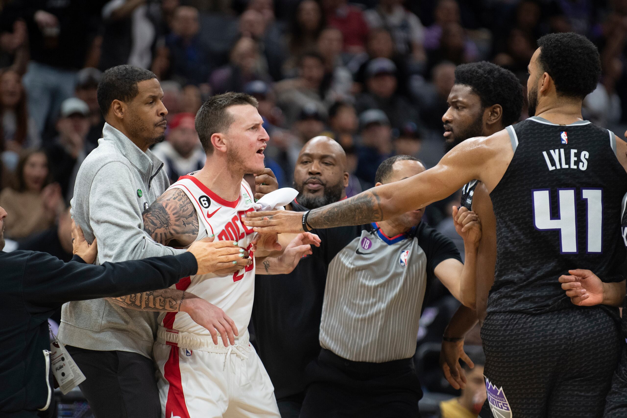 Garrison Mathews (25), de los Rockets de Houston, es detenido por el coach de los Rockets, Stephen Silas, mientras Mathews discute con Chimezie Metu y Trey Lyles (41), de los Kings de Sacramento, en duelo del viernes 13 de enero de 2023, en Sacramento, California.