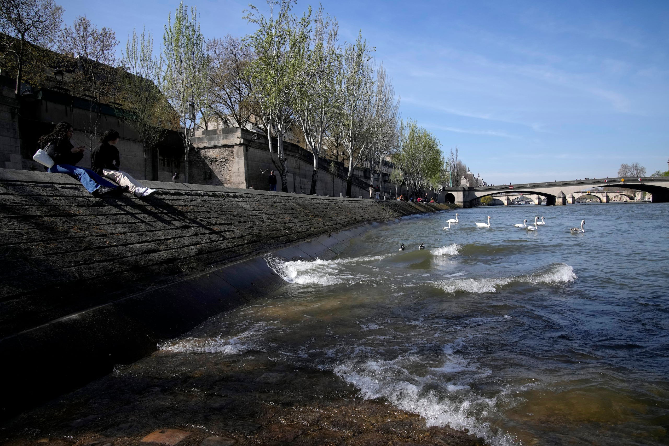 Gente relajándose en la orilla del Río Sena en París, el miércoles 5 de abril de 2023. Una costosa y compleja operación de limpieza está resucitando el Sena justo a tiempo para que tenga un papel protagonista en los Juegos de París de 2024 y más adelante pueda cumplir con su reputación de río más romántico del mundo, uno que de verdad sea apto para la gente. (AP Foto/Christophe Ena)