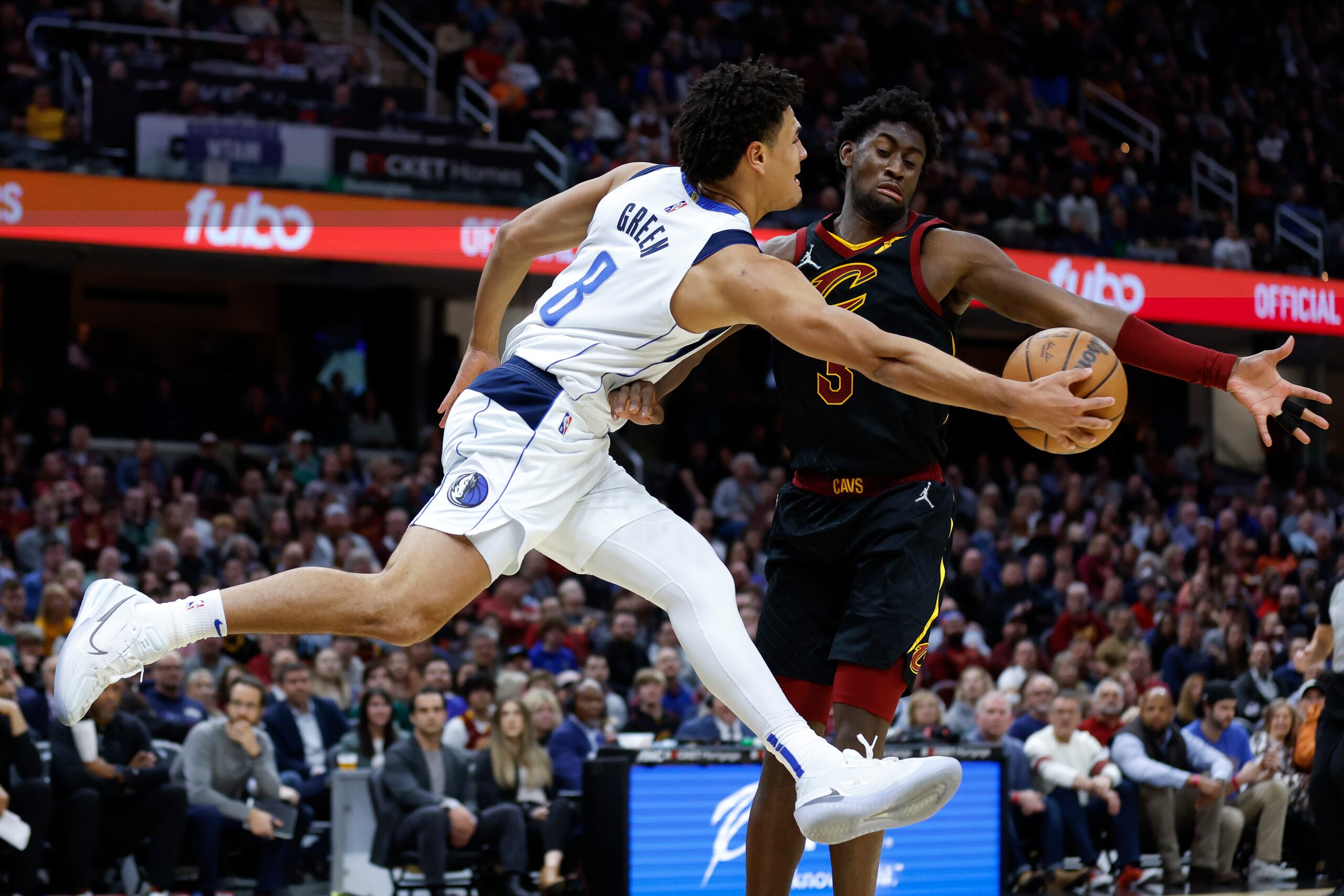 El defensa de los Mavericks de Dallas, Josh Green, a la izquierda, se suspende en el aire al realizar un pase ante la defensa de Caris LeVert, de los Cavaliers de Cleveland.