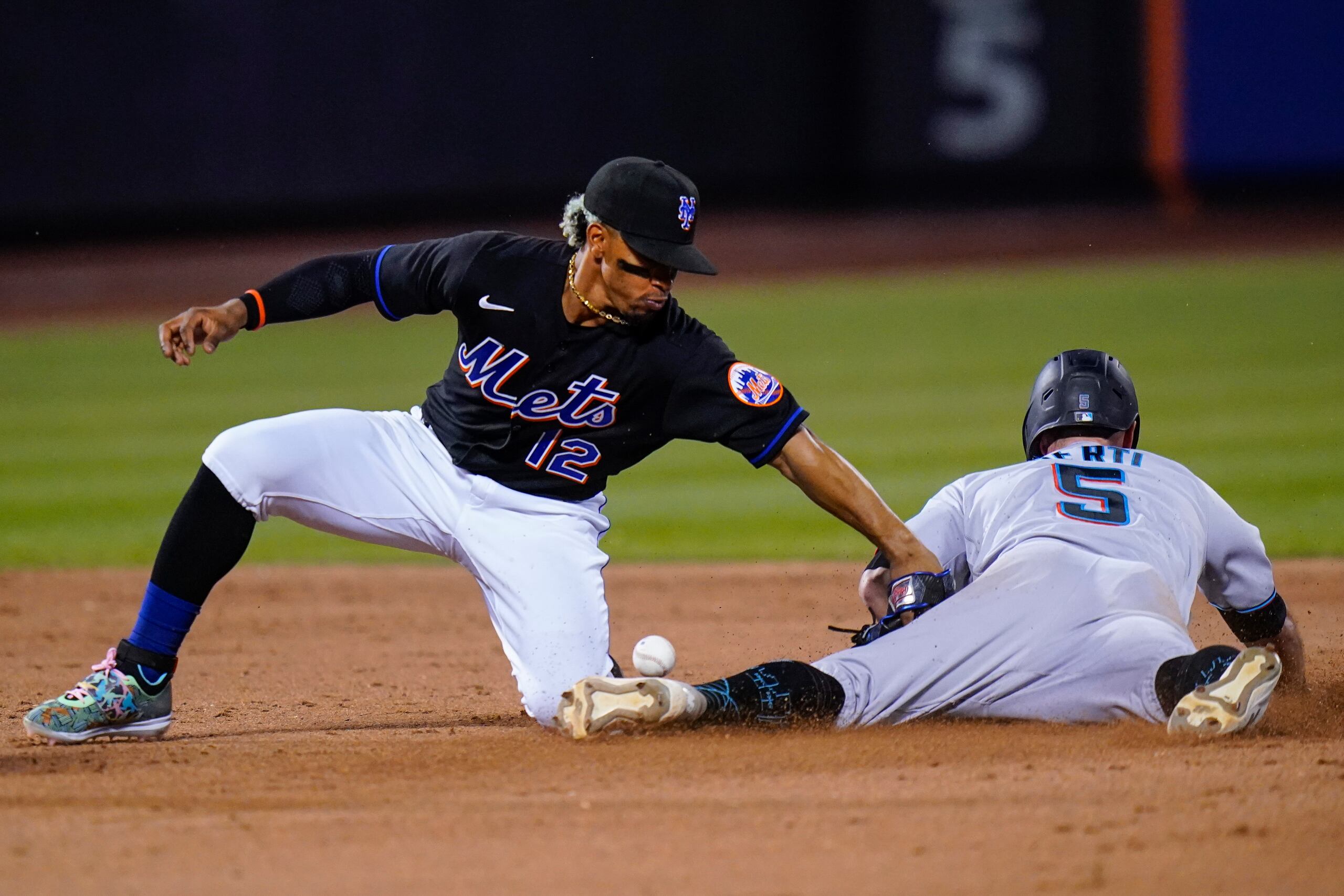 EL corredor de los Marlins de Miami, Jon Berti, se desliza a salvo en un intento de robo cuando el boricua Francisco Lindor, de los Mets, no puede retener la pelota.