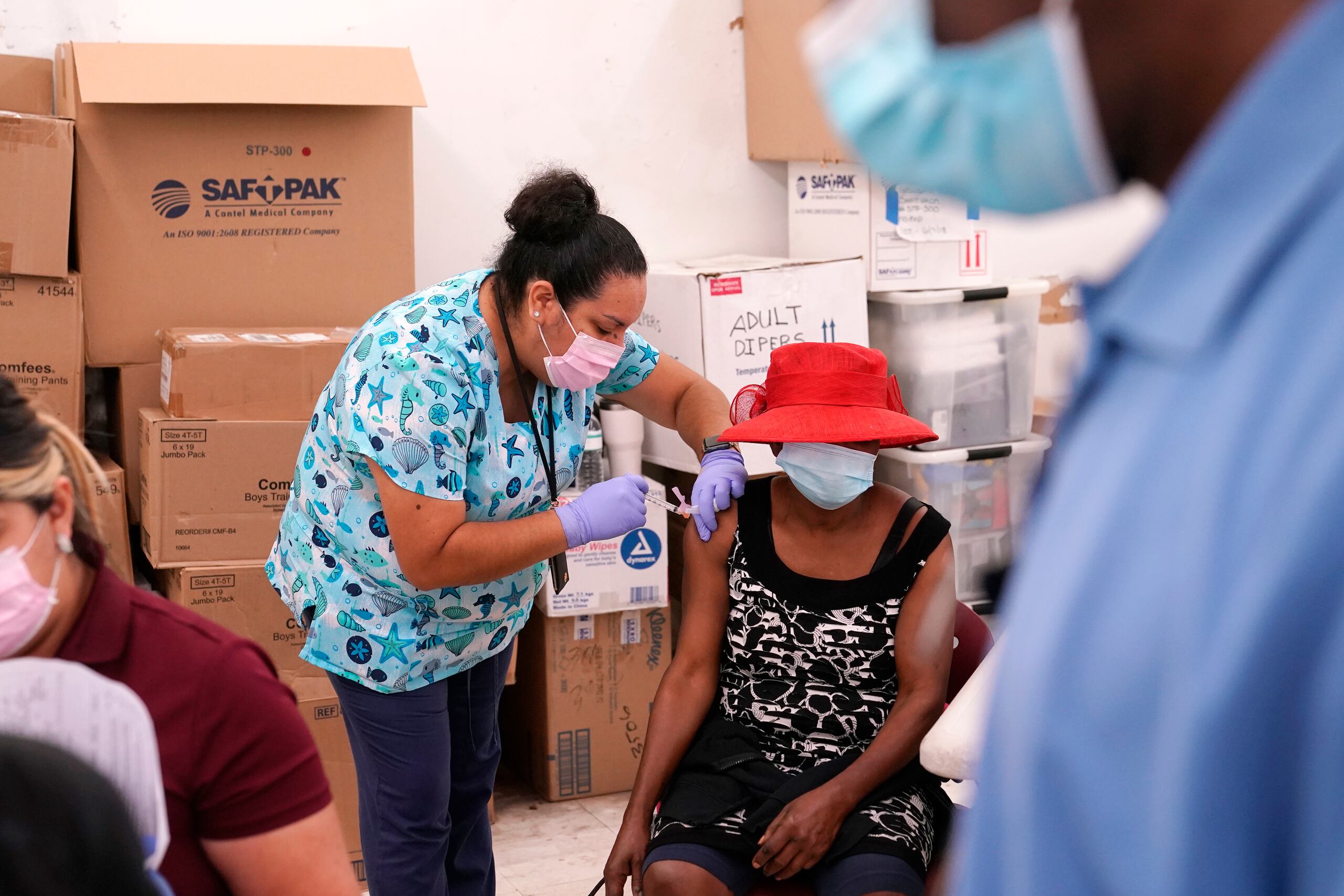 La enfermera Ashleigh Velasco, aplica una vacuna de Johnson & Johnson contra el COVID-19 a Rosemene Lordeus, a la derecha, en una clínica a cargo de Health Network, en Immokalee, Florida.