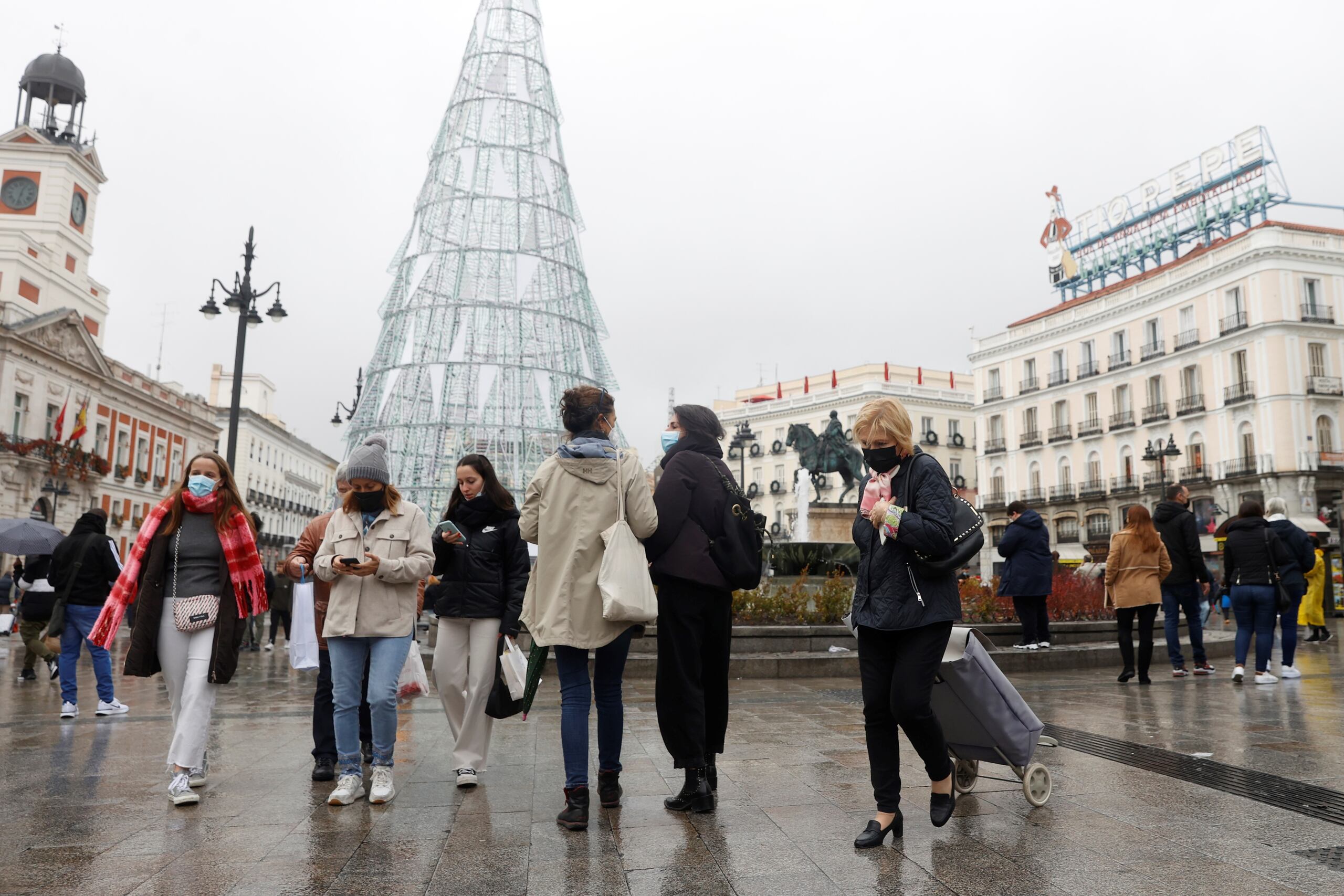 Varias personas caminan con mascarillas por la Puerta del Sol este viernes. EFE/ JuanJo Martín
