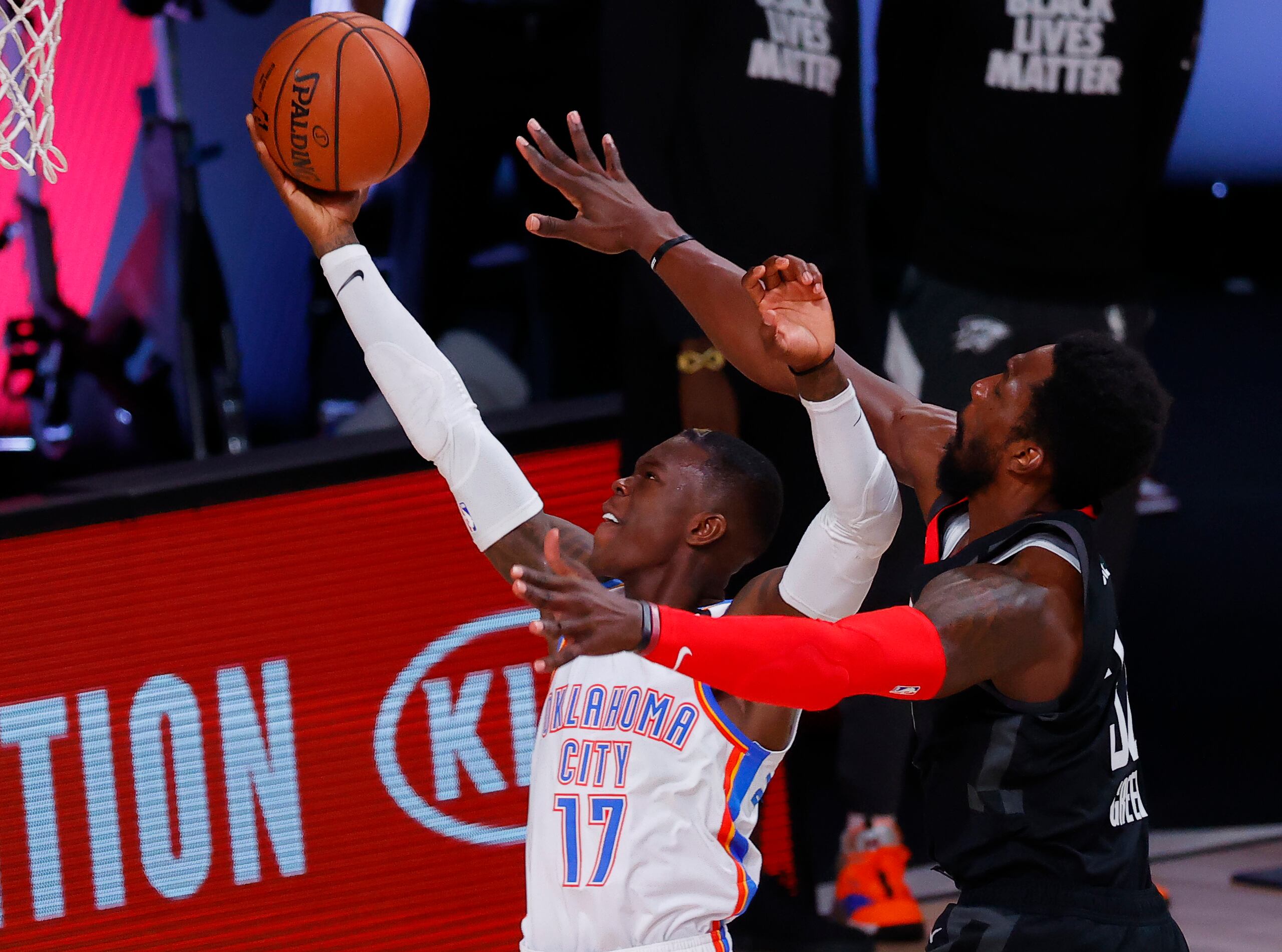 Dennis Schroder (17), del Thunder de Oklahoma City, realiza un intento ante la apretada defensa de Jeff Green, de los Rockets de Houston, durante el choque del lunes.