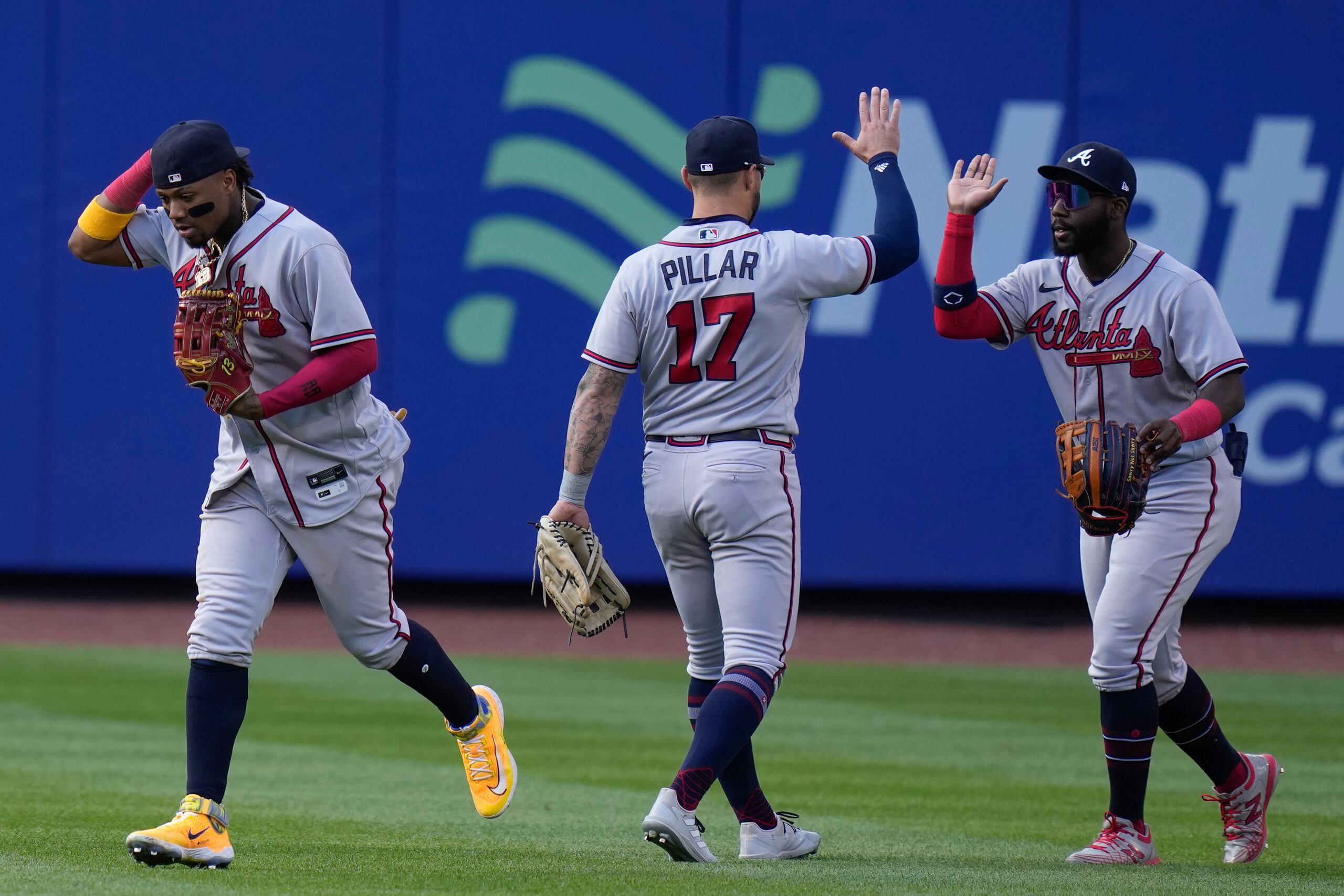 Desde la izquierda, los jardineros Ronald Acuña Jr., Kevin Pillar y Michael Harris II de los Bravos de Atlanta celebran tras la victoria ante los Mets de Nueva York en el primer juego de una doble cartelera, el lunes 1 de mayo de 2023, en Nueva York. (AP Foto/Seth Wenig)