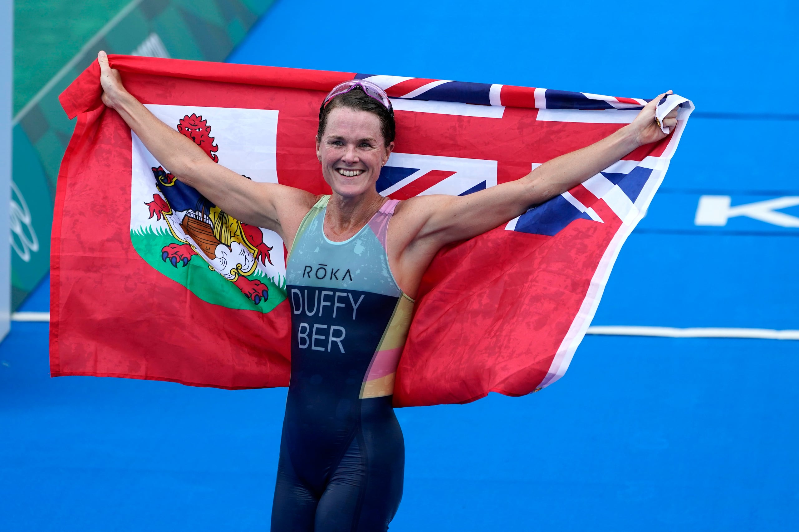 Flora Duffy, de Bermuda, muestra la bandera que representa luego de ganar el oro en el tríalo individual femenino de los Juegos de Tokio 2020.