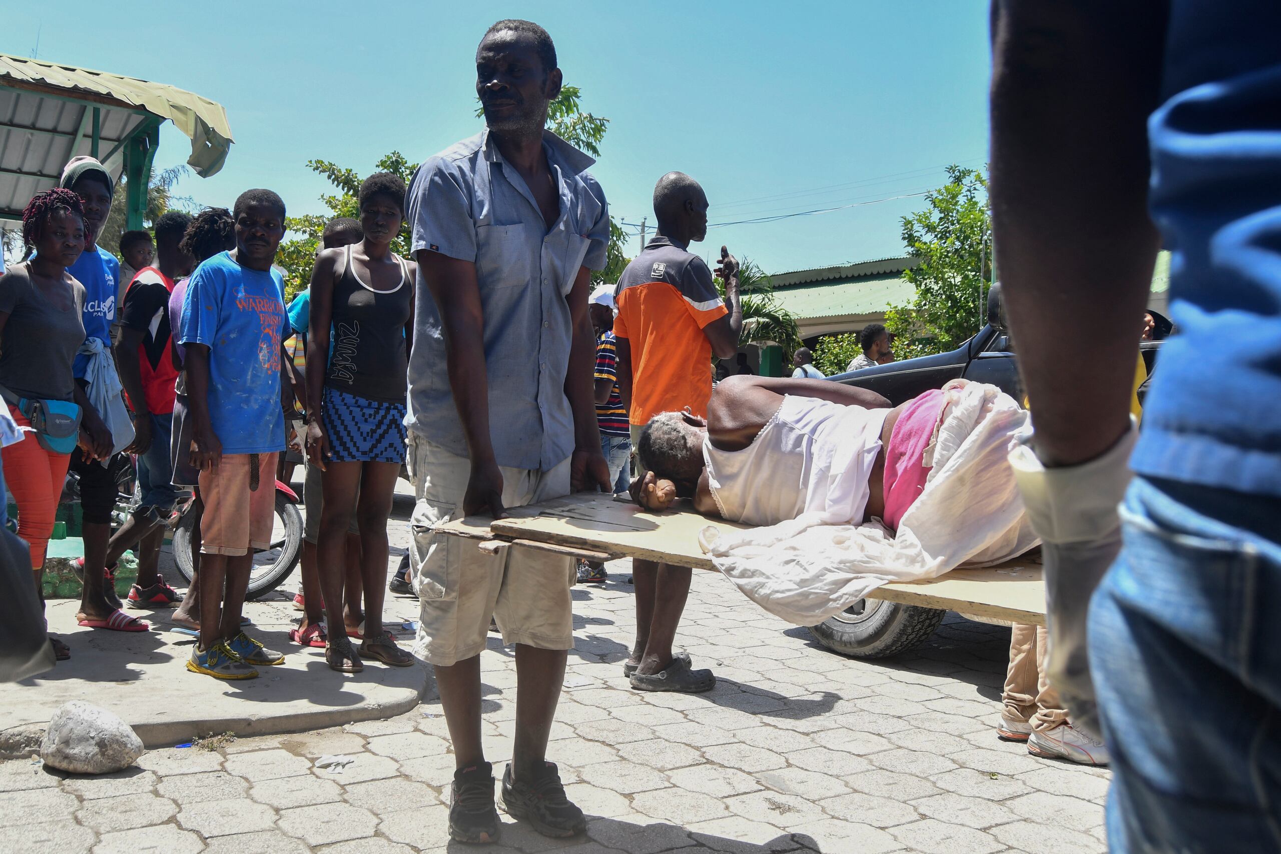 Un hombre ayuda a transportar a una persona rescatada de los escombros tras un terremoto en Les Cayes, Haití.