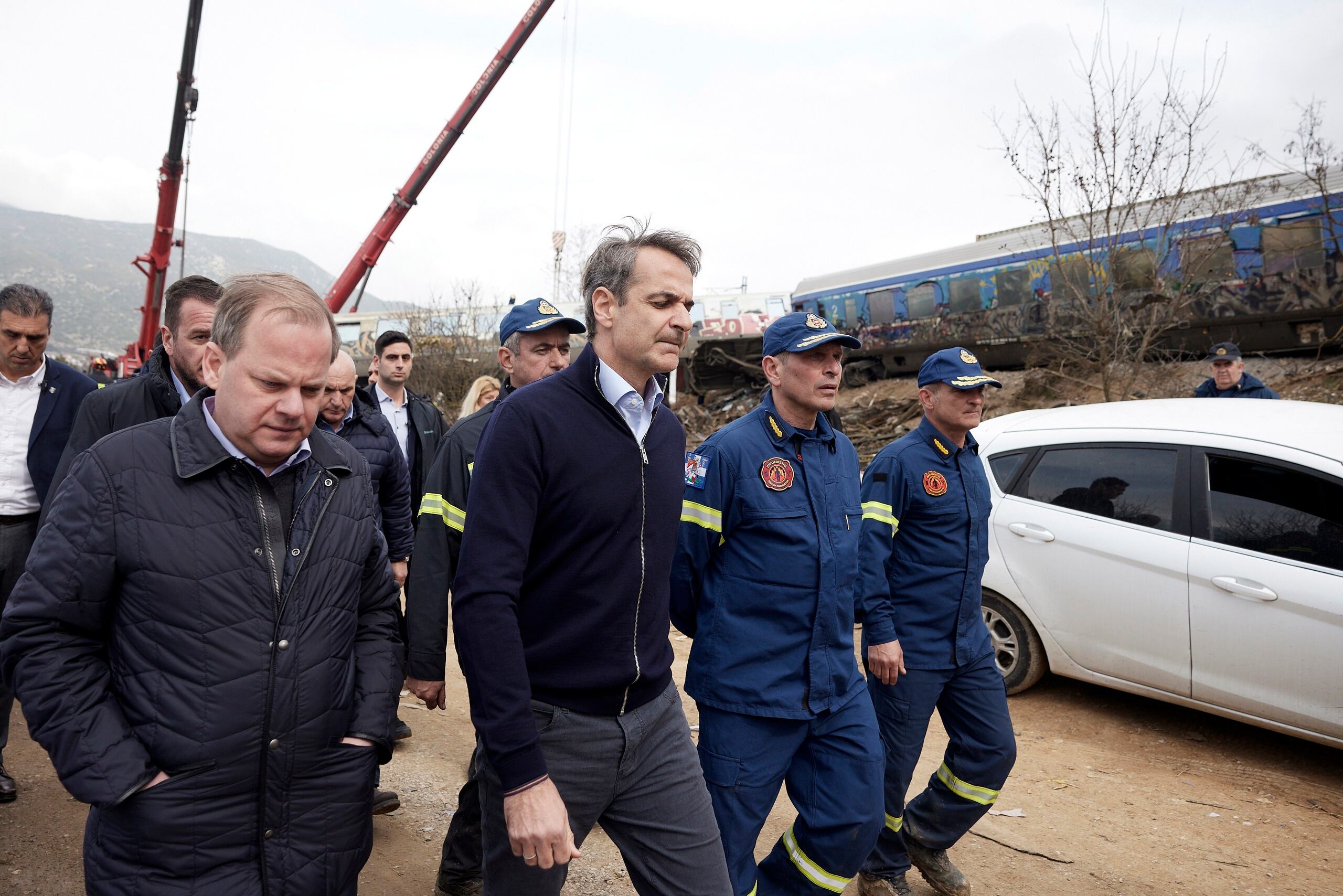 El primer ministro de Grecia, Kyriakos Mitsotakis, en el centro, llegó a la escena con el jefe saliente de transporte, Kostas Karamanlis, a la izquierda, quien presentó su renuncia horas después del incidente que dejó a más de 40 personas muertas.