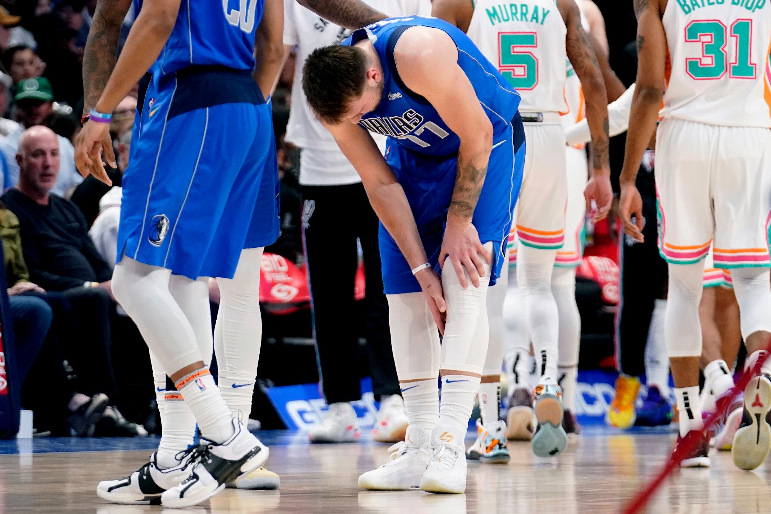 El jugador de los Mavericks de Dallas Luka Doncic (77) se palpa la pantorrilla tras lastimarse en la segunda mitad de su juego de NBA contra los Spurs de San Antonio, el domingo 10 de abril de 2022 en Dallas. (AP Foto/Tony Gutierrez)