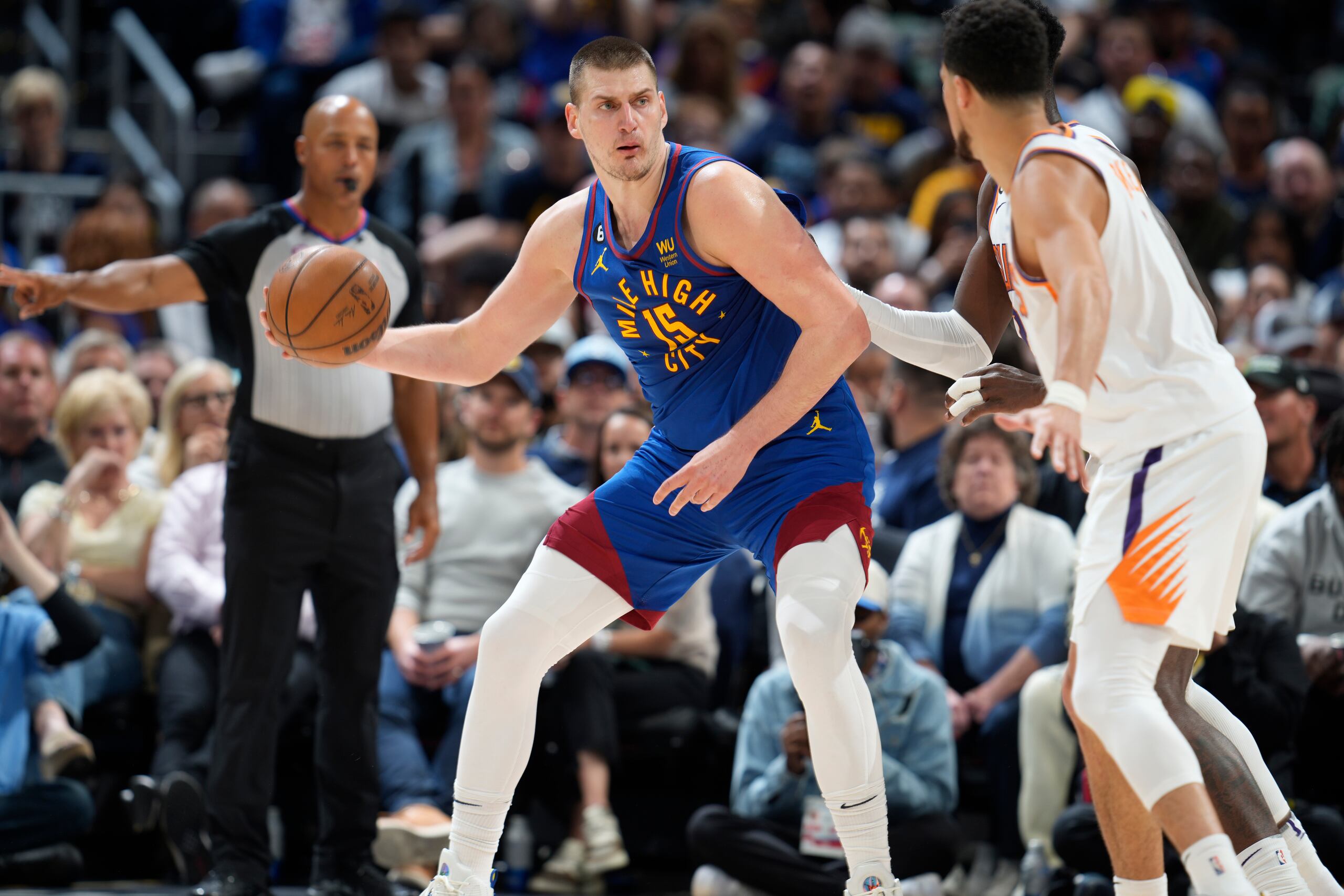 El serbio Nikola Jokic, de los Nuggets de Denver, busca enviar un pase frente a Devin Booker, de los Suns de Phoenix, durante el encuentro del sábado.