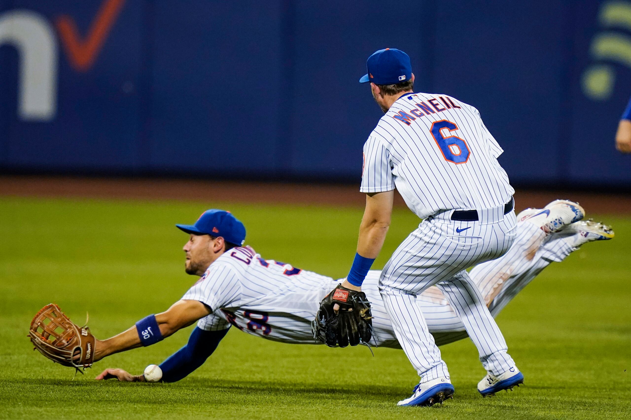 A la izquierda, Michael Conforto, de los Mets, pierde el control de la pelota en un batazo de Alex Dickerson, de los Giants, mientras Jeff McNeil observa la jugada.