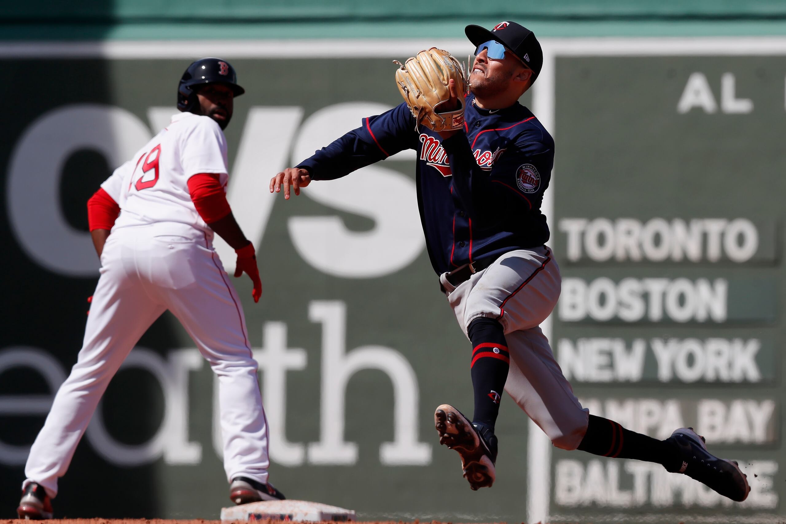 Carlos Correa realiza un movimiento para atrapar un débil batazo de Rafael Devers mientras Jackie Bradley Jr. (19) lo observa detenido sobre la segunda base.