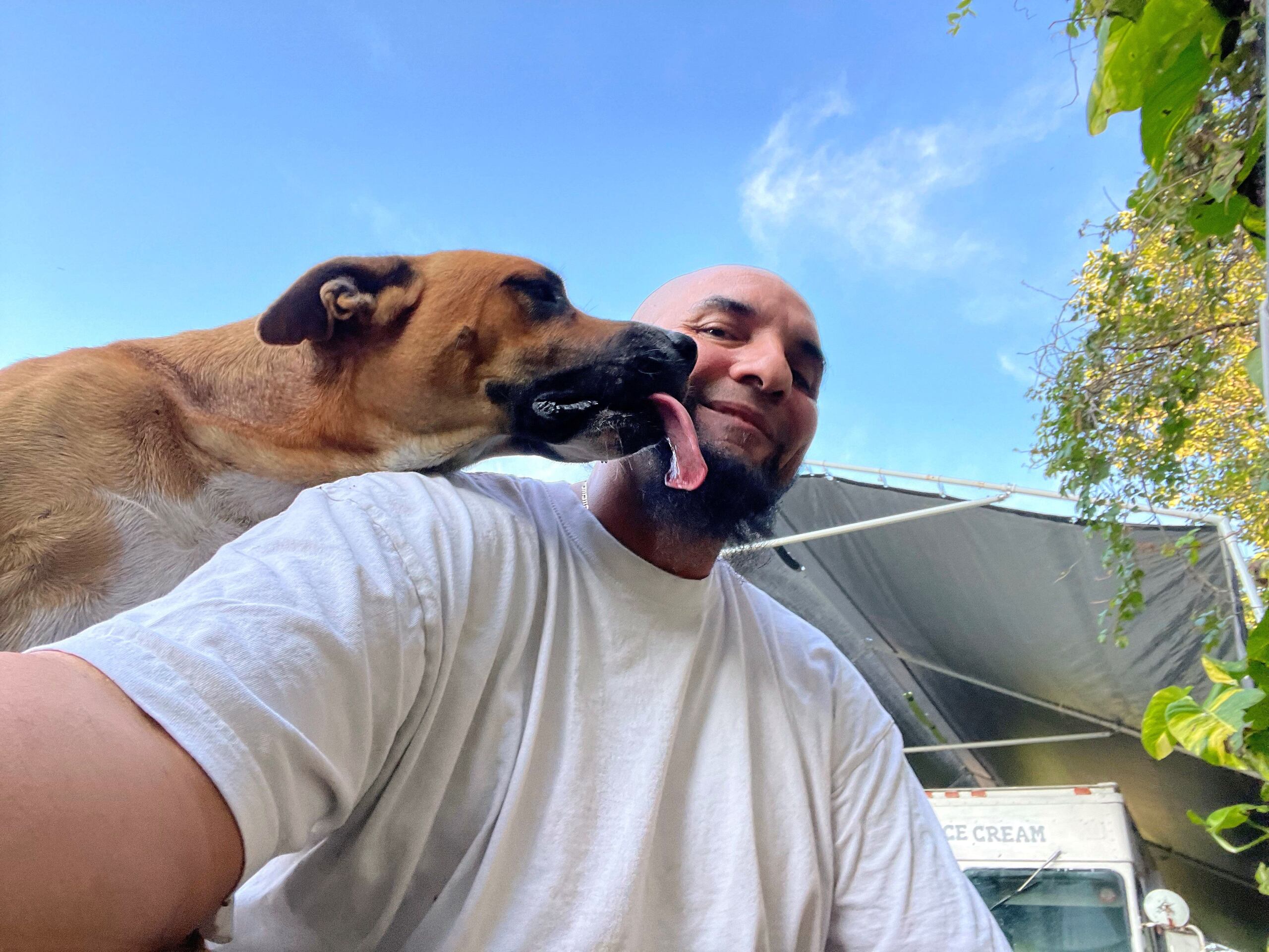 César junto a uno de sus dos perros en la puerta de su casa en el norte de Miami-Dade, Florida. La mitad de las mascotas de Estados Unidos viven en hogares de recursos limitados como el de César, que no puede trabajar regularmente por una enfermedad mental y cada día "se las tiene que buscar" para asegurarse comida para él, su hijo y sus dos perros, a los que no quiere renunciar por no tener dinero. EFE/ César