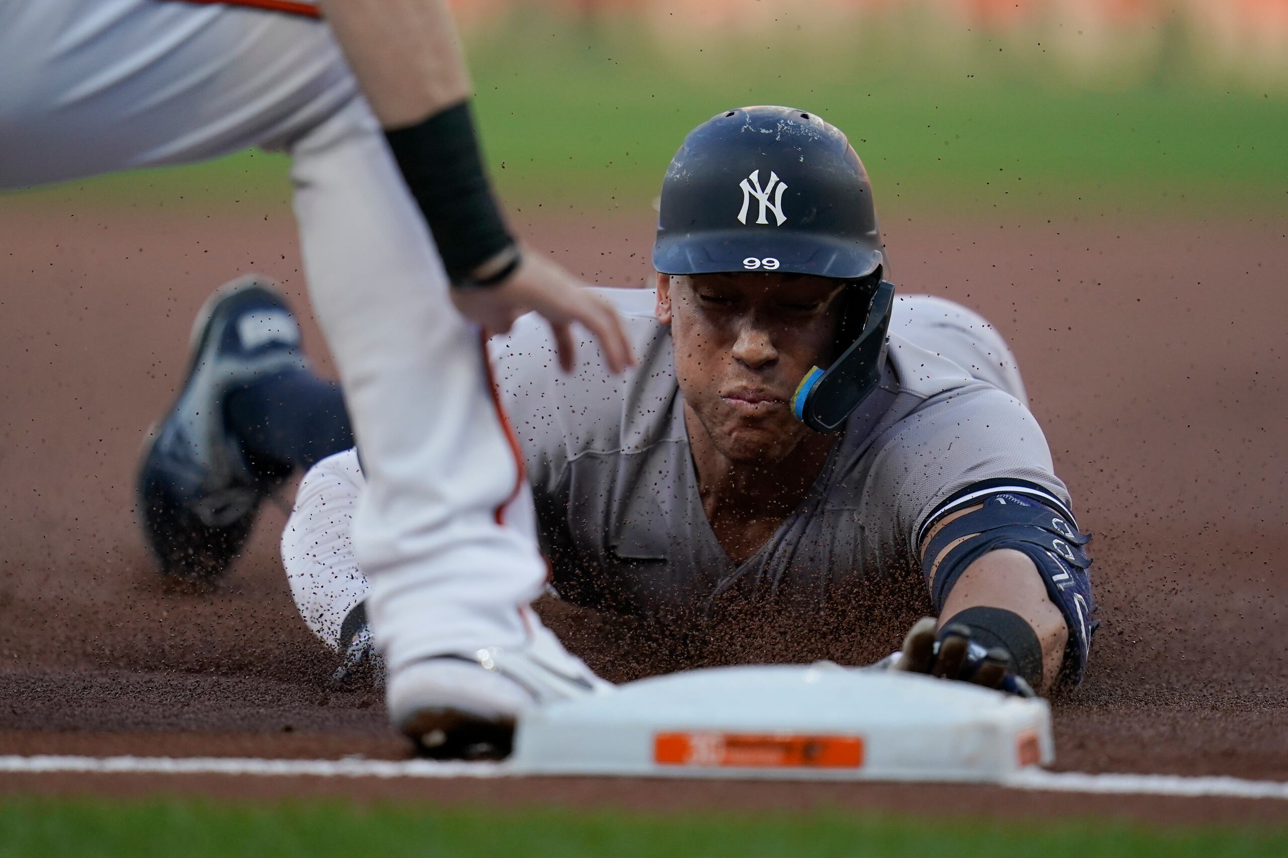 Aaron Judge, de los Yankees de Nueva York, se desliza en tercera base ante Tyler Nevin, de los Orioles de Baltimore, quien lo puso fuera en la primera entrada.