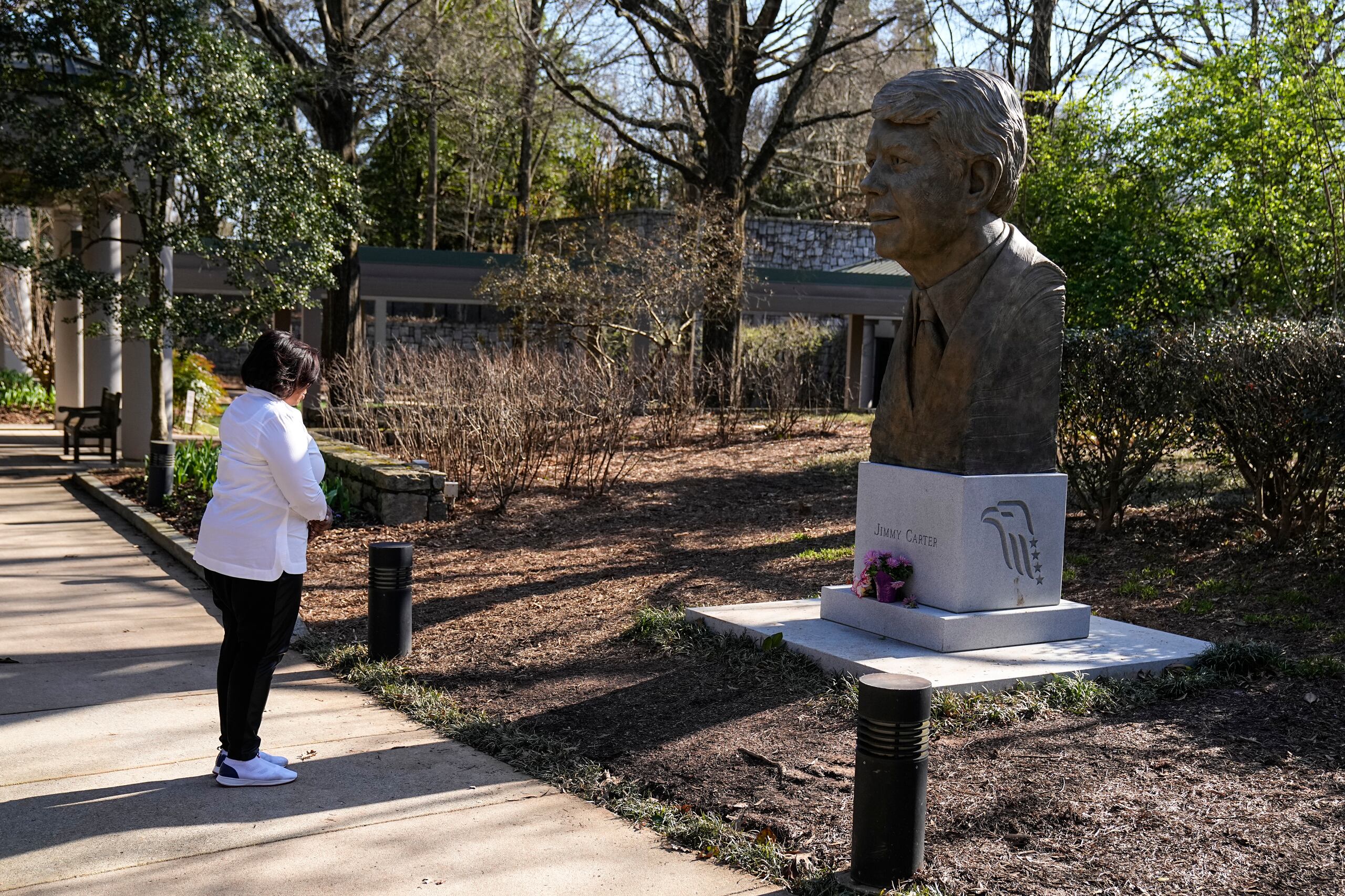 Dawn Thomas de Kankakee Illinois, ofrece una pequeña oración al presidente Jimmy Carter en la Biblioteca y Museo Presidencial de Jimmy Carter, el domingo 19 de febrero de 2023, en Atlanta. (AP Foto/John Bazemore)