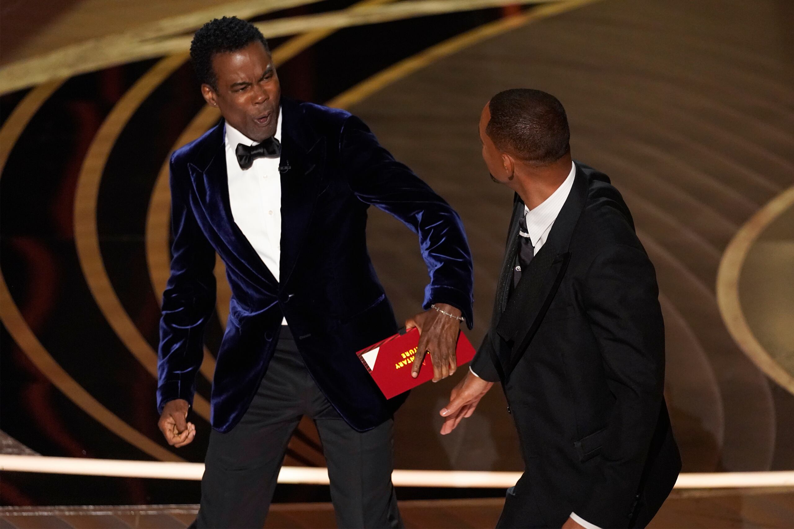 El momento que Chris Rock reacciona a la bofetada de Will Smith en pleno escenario durante la entrega de los premios Oscar el 27 de marzo de 2022 en el Teatro Dolby, en Los Ángeles.