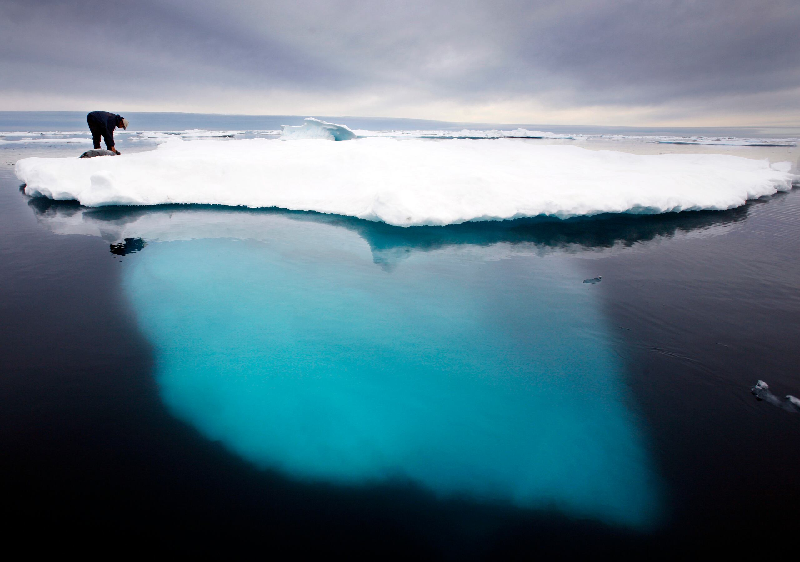 Un cazador de focas inuit toca una foca muerta sobre un iceberg derretido cerca de la isla de Ammassalik, en Groenlandia.