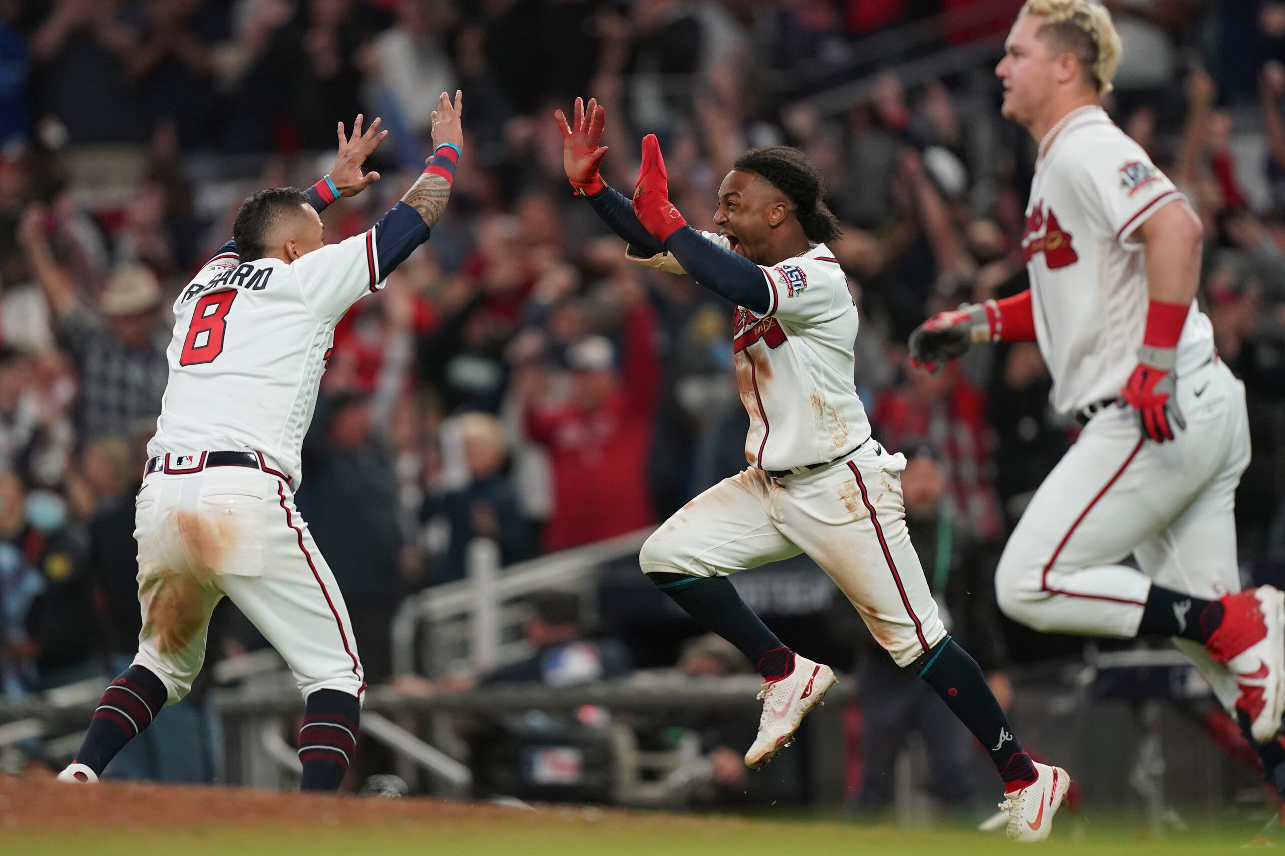 Ozzie Albies, en el centro, celebra con el boricua Eddie Rosario (8) luego de que Albies anotara la carrera del triunfo ante los Dodgers el sábado. A la derecha, Joc Pederson.