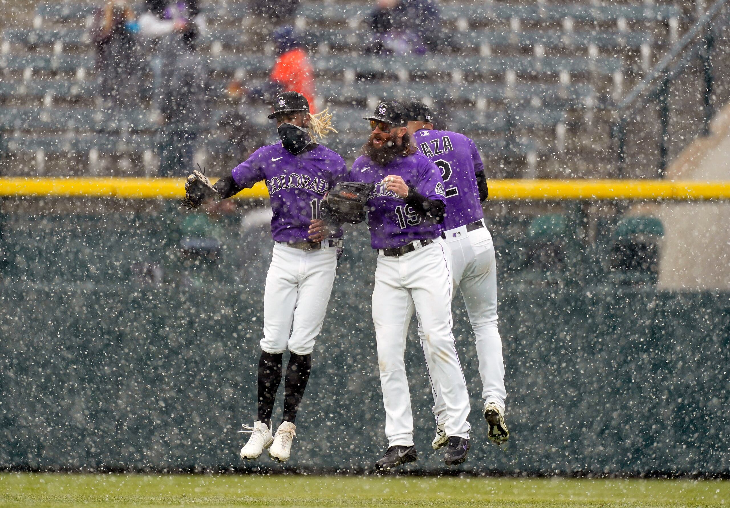 Desde la izquierda, Raimel Tapia, Yonathan Daza y Charlie Blackmon, jardineros de los Rockies, celebran bajo la nieve su triunfo del miércoles sobre Houston.