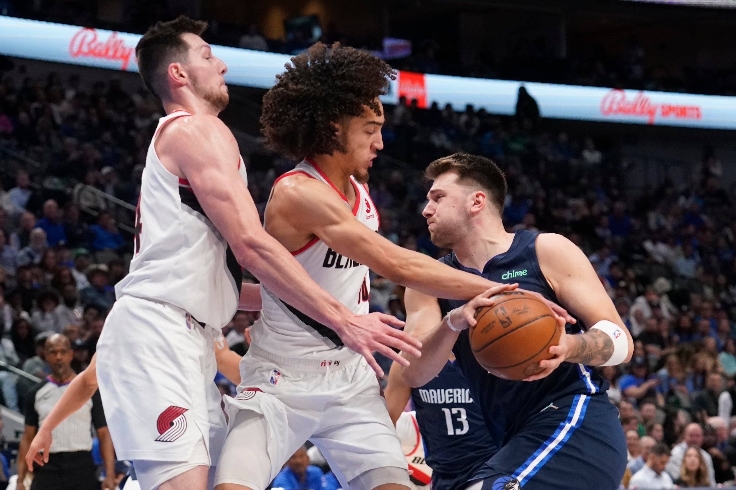 Luka Doncic, a la derecha, intenta retener el balón mientras avanza contra la defensa de CJ Elleby, en el centro, y Drew Eubanks, a la izquierda, de los Blazers de Portland.