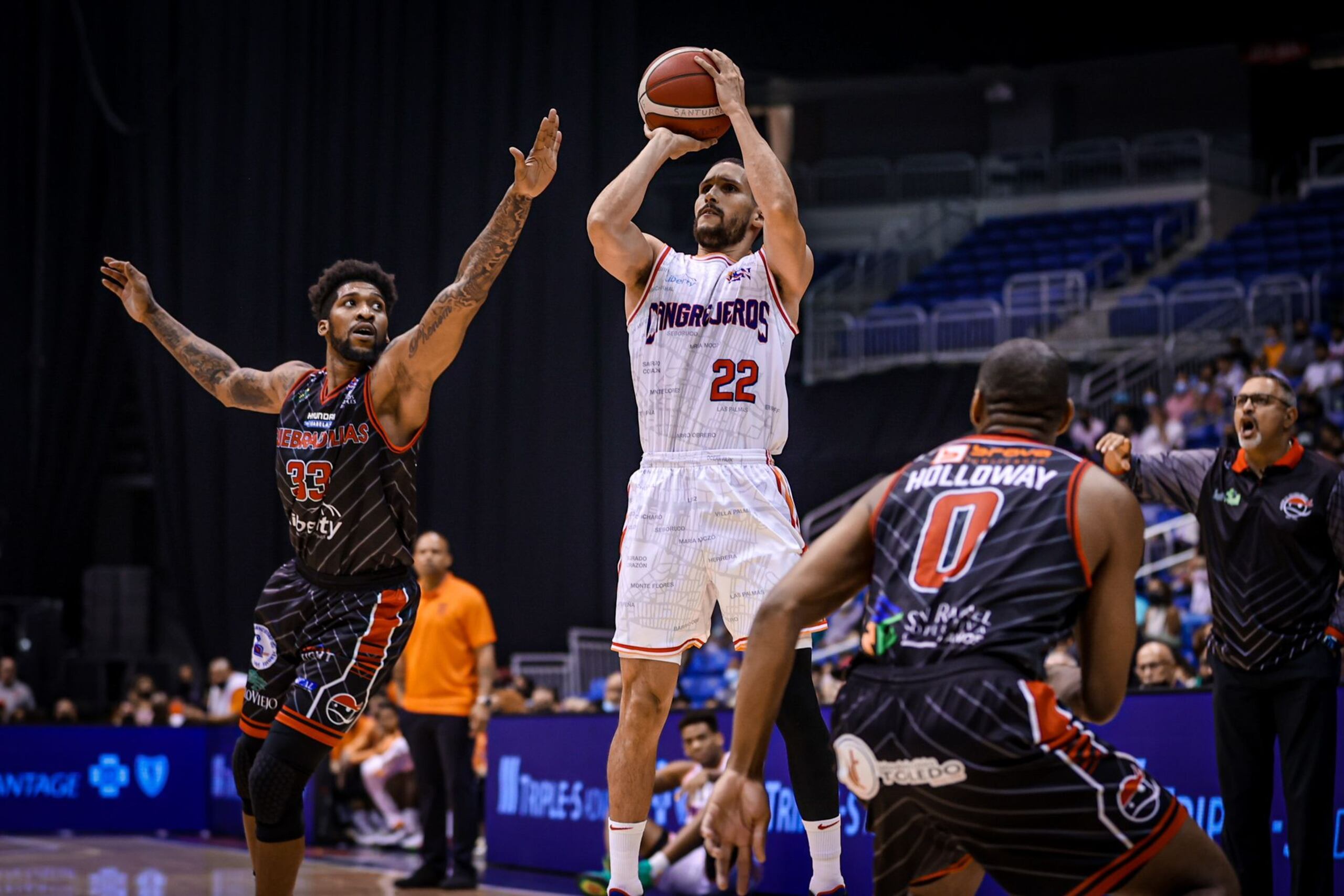 Isaac Sosa, de los Cangrejeros, se levanta para realizar un disparo mientras Carlos Emory, a la izquierda, intenta evitarlo. Observa el pirata Tu Holloway (0). 

28 agosto 2021