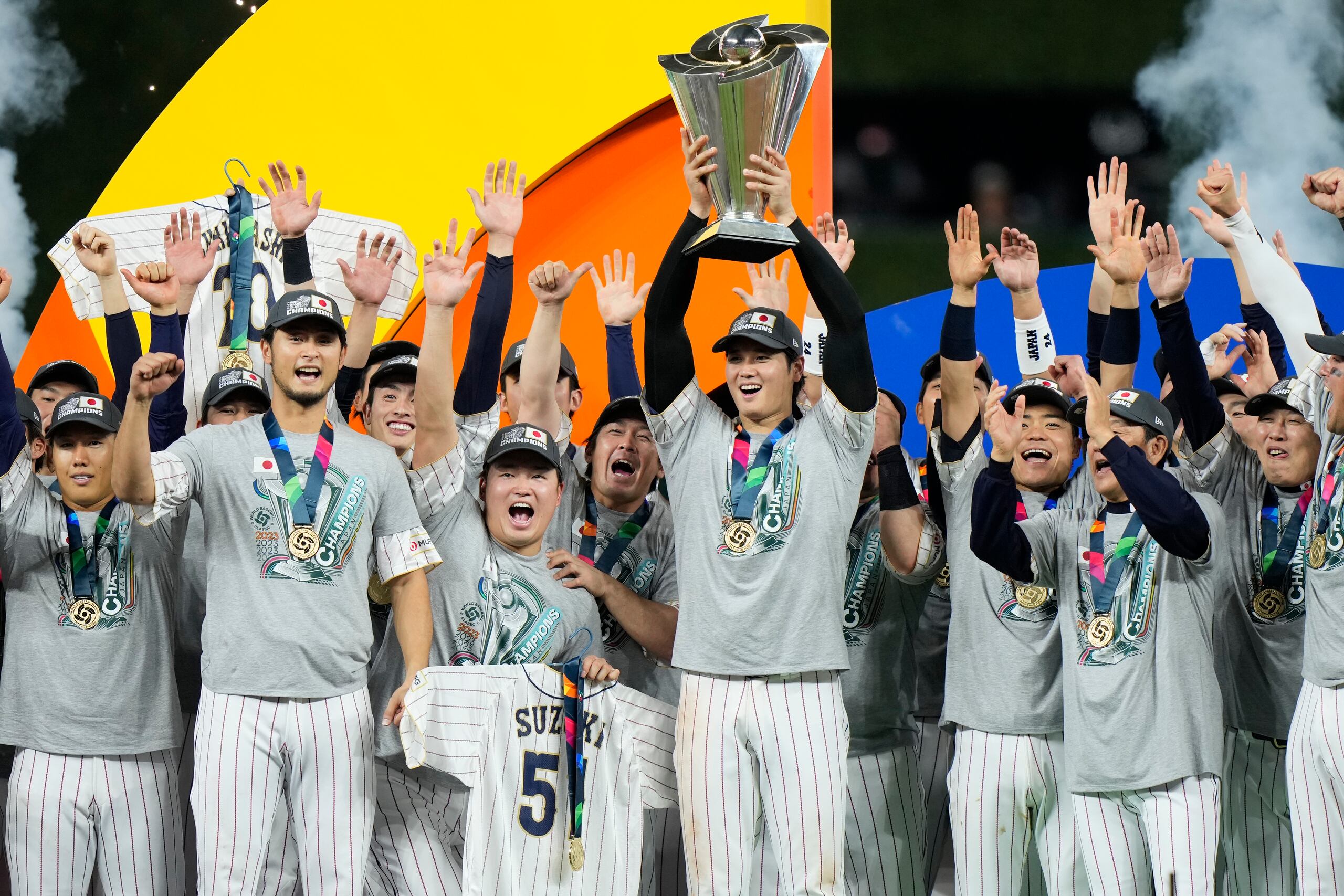 El lanzador Shohei Ohtani, Jugador Más Valioso de la final del Clásico Mundial de Béisbol, levanta el trofeo de campeón rodeado de sus compañeros del equipo de Japón.