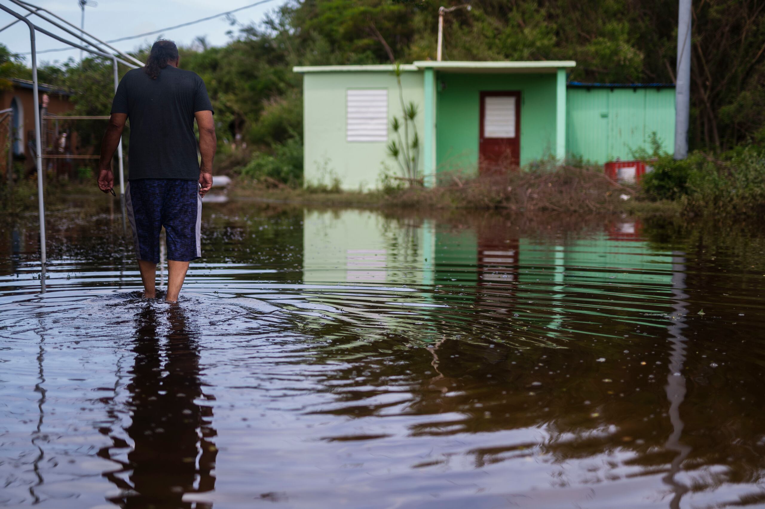 Un residente del barrio Pozuelo de Guayama camina por la inundación causada por el huracán Fiona.