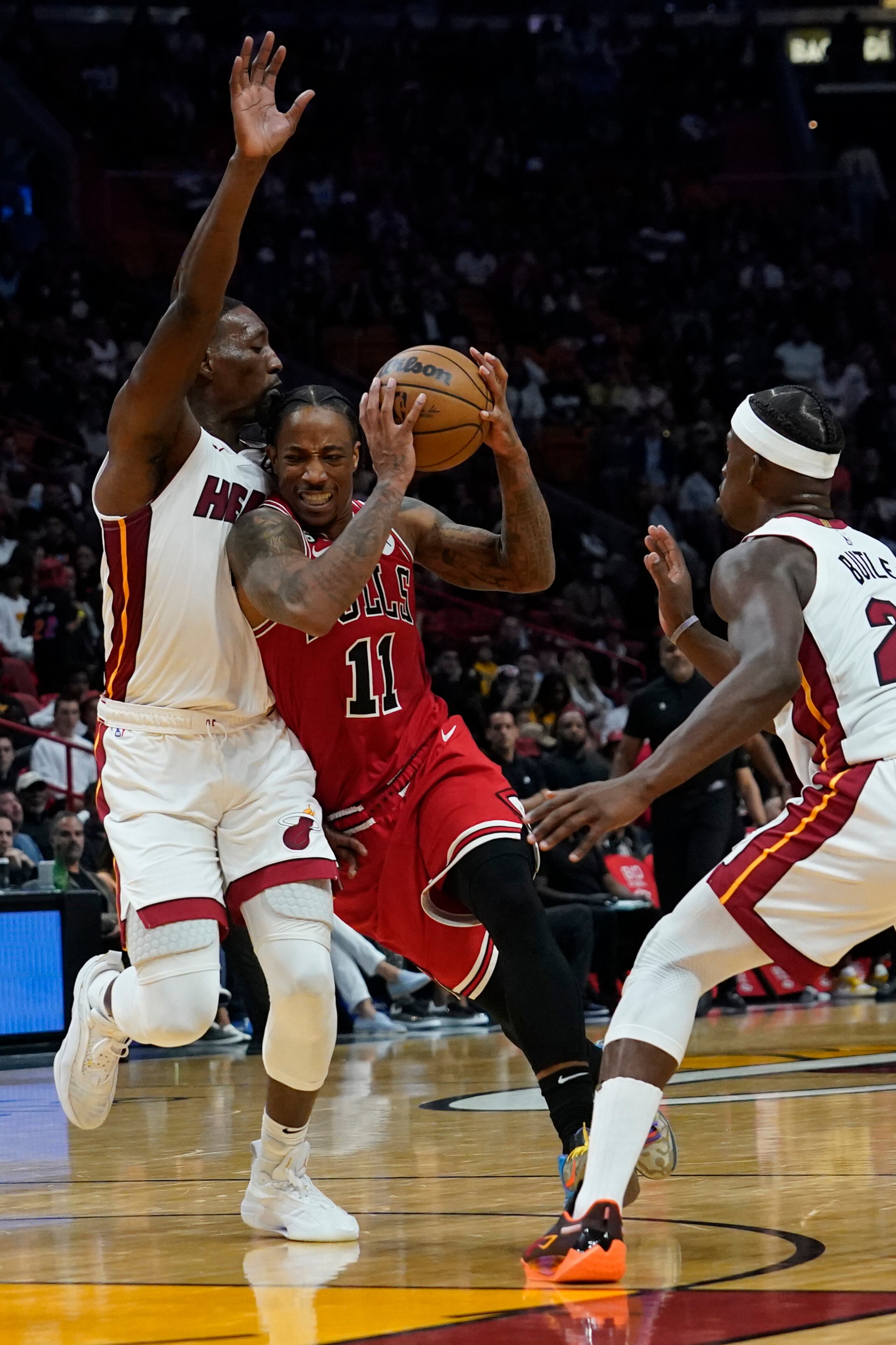 El delantero de los Bulls de Chicago, DeMar DeRozan (11), se dirige al canasto entre la defensa de Bam Adebayo, a la izquierda y Jimmy Butler, del Heat de Miami, durante el partido del miércoles.