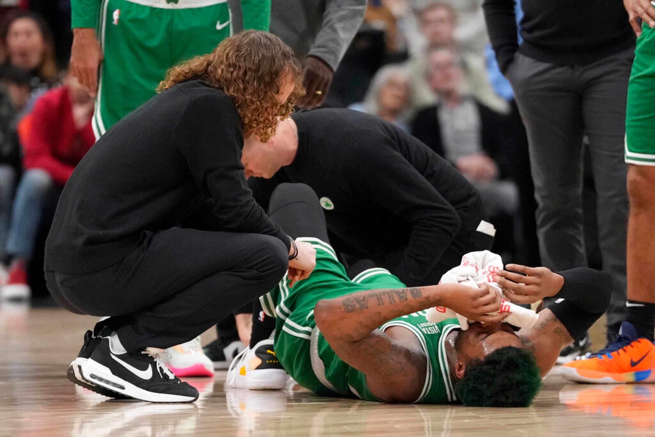 Los entrenadores atienden a Marcus Smart después de lesionarse un tobillo.