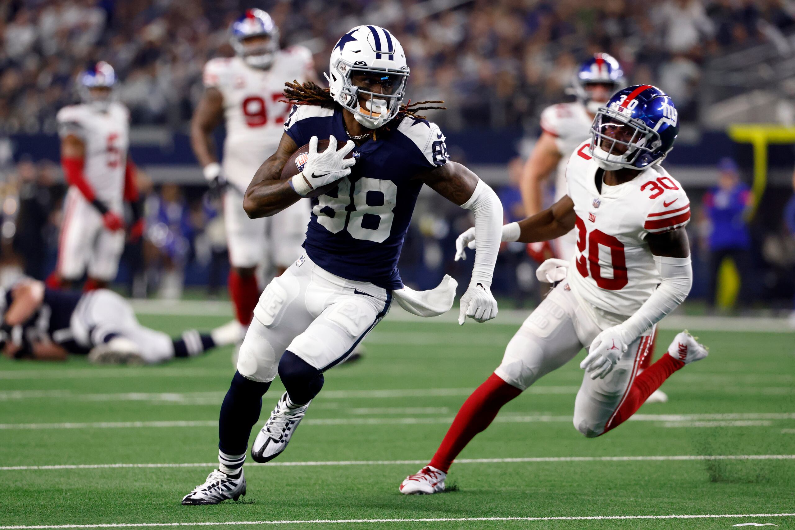 El receptor abierto de los Cowboys de Dallas, CeeDee Lamb (88), elude la marca del cornerback Darnay Homes (30), de los Giants de Nueva York, en la segunda mitad del partido de la NFL en Arlington, Texas, el jueves 24 de noviembre de 2022. (AP Foto/Ron Jenkins)