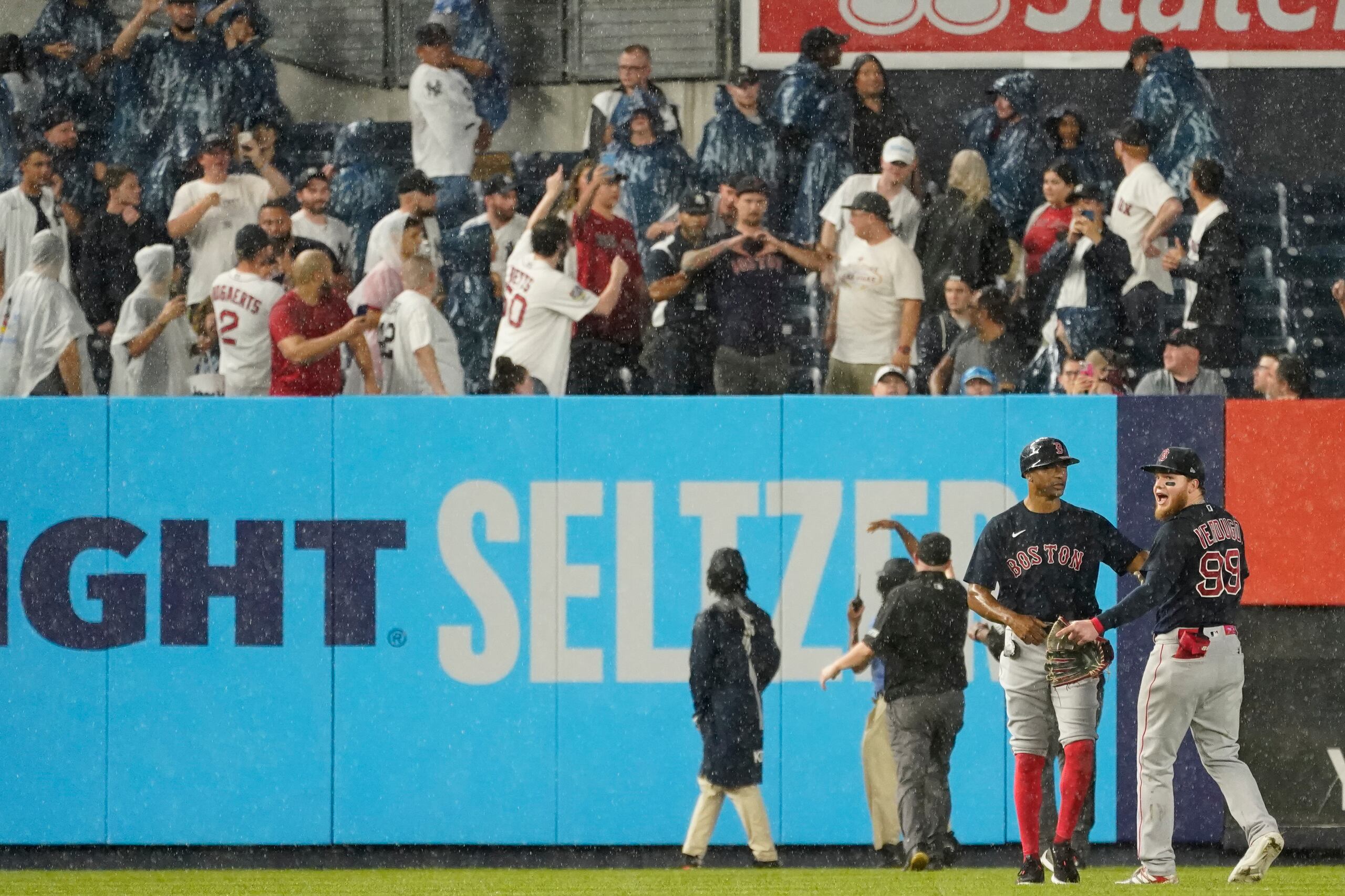 El entrenador de primera base de los Medias Rojas de Boston, Tom Goodwin, calma al jardinero Alex Verdugo luego de ser golpeado en la espalda por un objeto lanzado por un fanático el 17 de julio de 2021 en Nueva York.