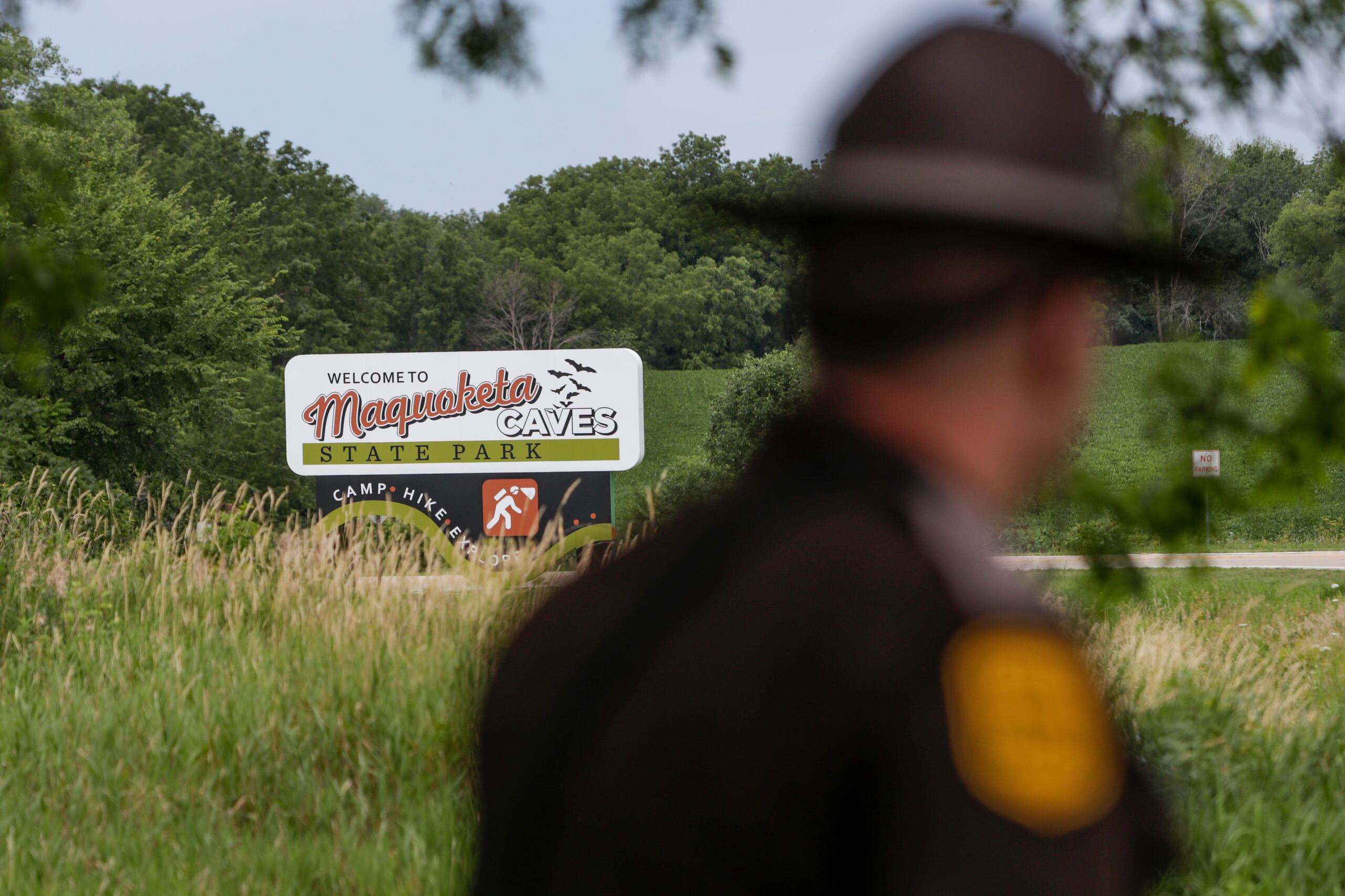 Un patrullero estatal de Iowa pasa junto a un letrero del Parque Estatal Maquoketa Caves mientras la Policía investiga un tiroteo que dejó a varias personas muertas, el viernes, 22 de julio, en Maquoketa, Iowa. El campamento fue evacuado a raíz del tiroteo. (Nikos Frazier/Quad City Times vía AP)