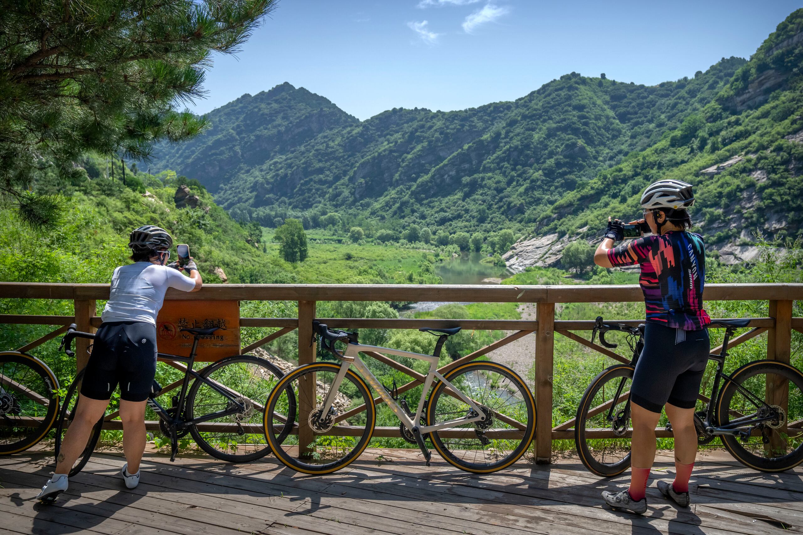 Yang Lan (der) toma una foto del paisaje durante un recorrido en bicicleta por una zona rural de las afueras de Beijing el 13 de julio del 2022. (AP Photo/Mark Schiefelbein)