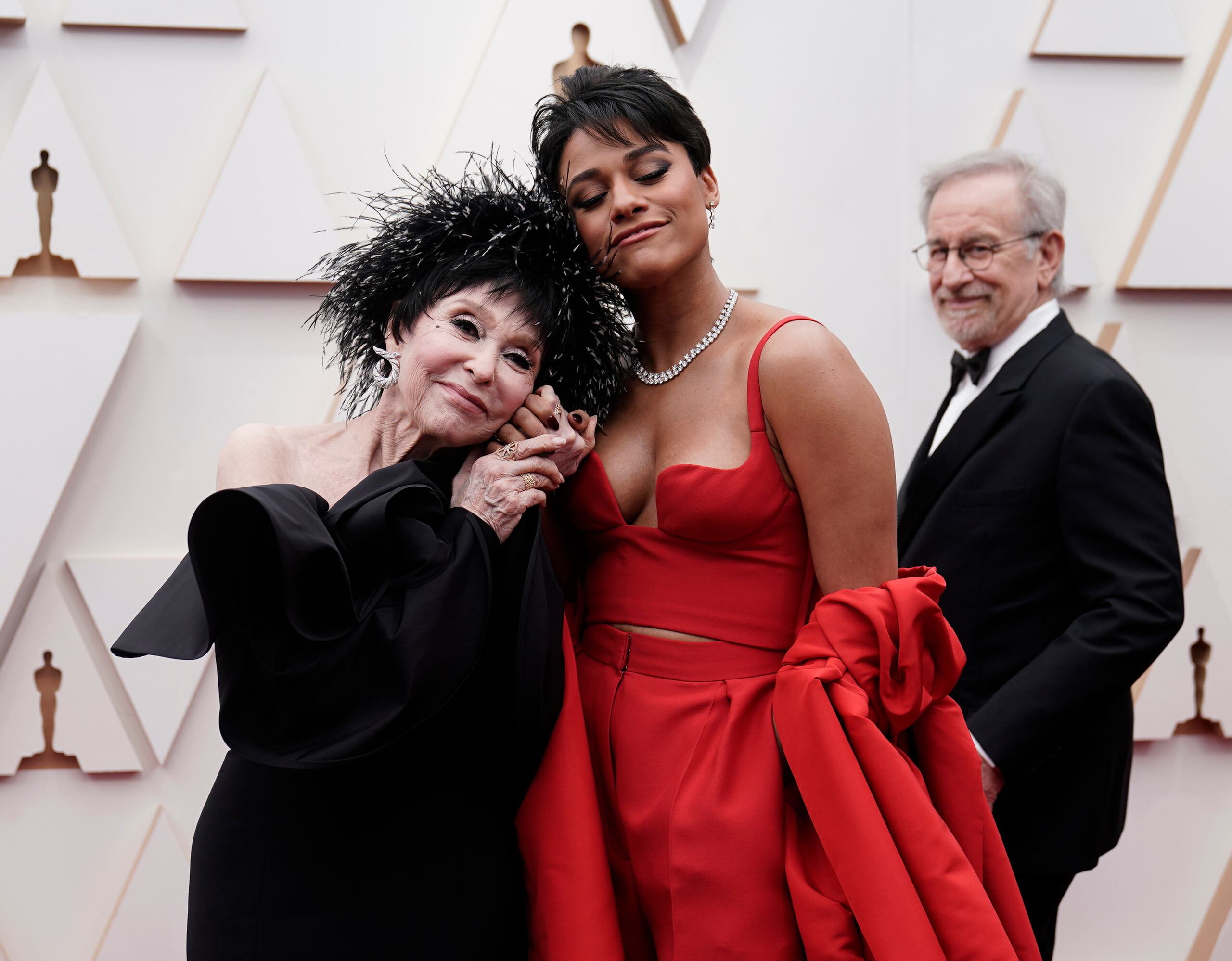 Rita Moreno, izquierda, y Ariana DeBose llegan a los Oscar el 27 de marzo de 2022 en el Teatro Dolby en Los Angeles. Al fondo mira Steven Spielberg. (Foto AP/Jae C. Hong)