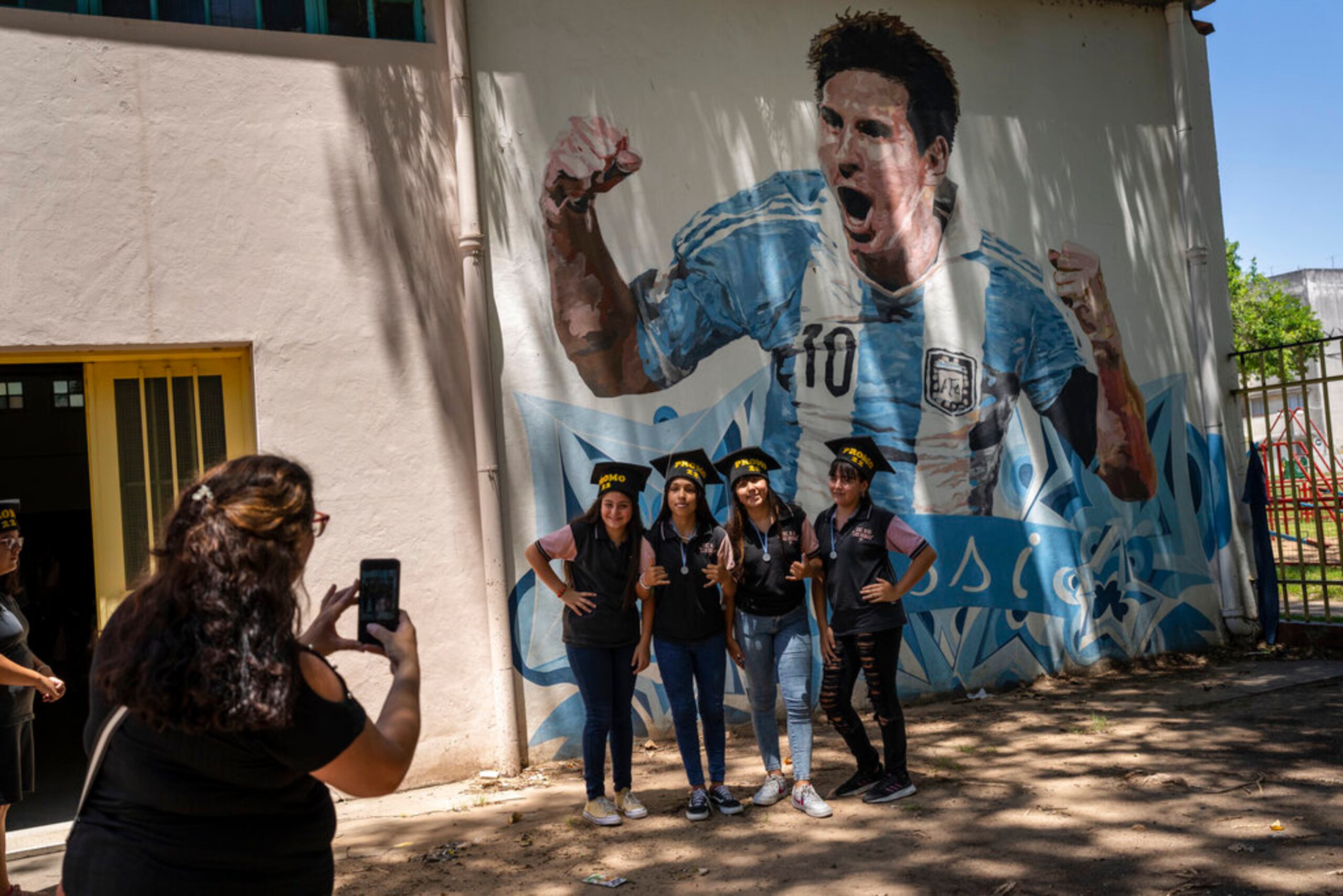 Estudiantes egresados de las escuela primaria General Las Heras, donde Lionel Messi hizo sus estudios, posan para una foto frente a un mural del futbolista, en el último día de clases, en Rosario, Argentina.