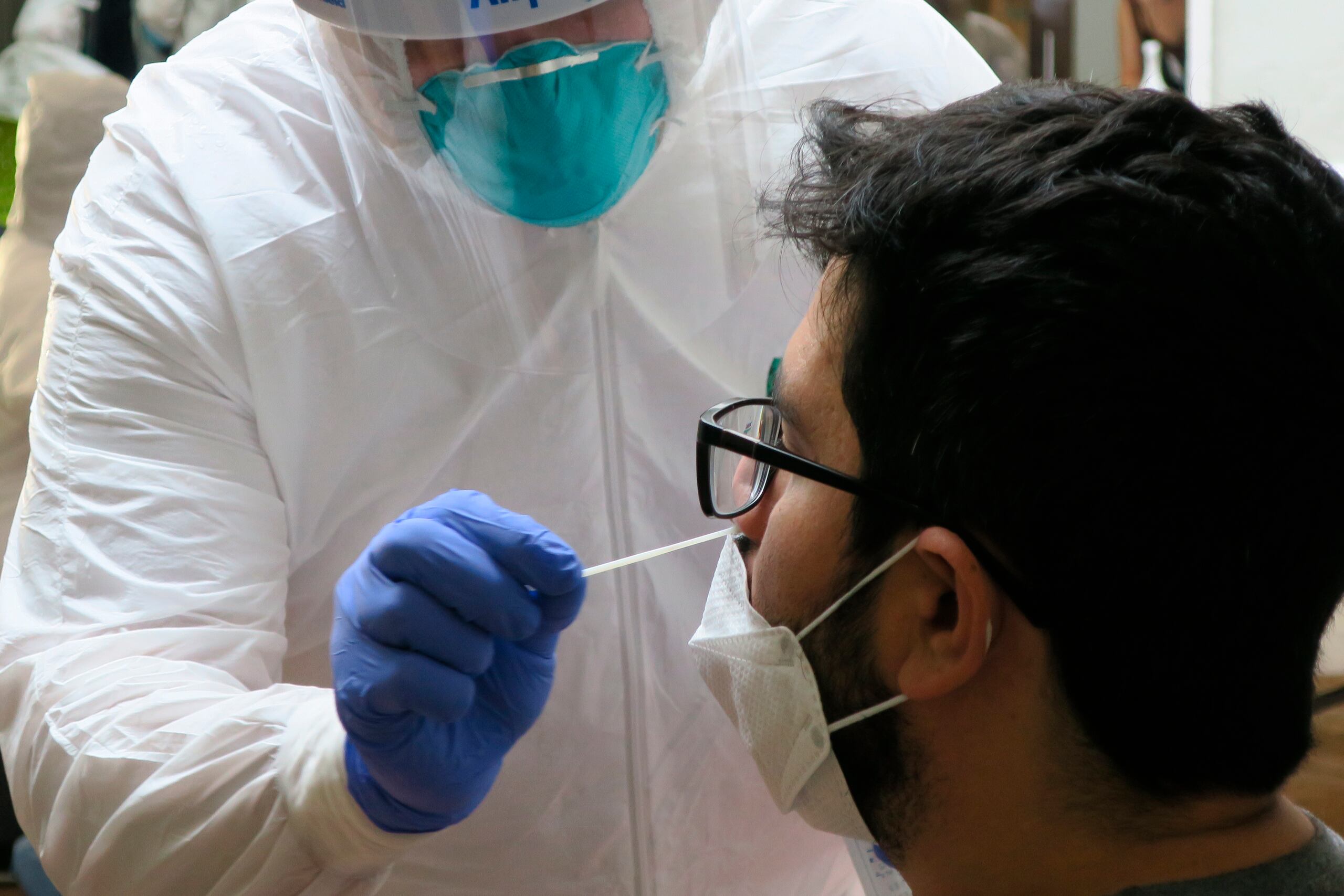 Un técnico de laboratorio inserta un hisopo en la nariz de un residente para la prueba del coronavirus en San Juan.