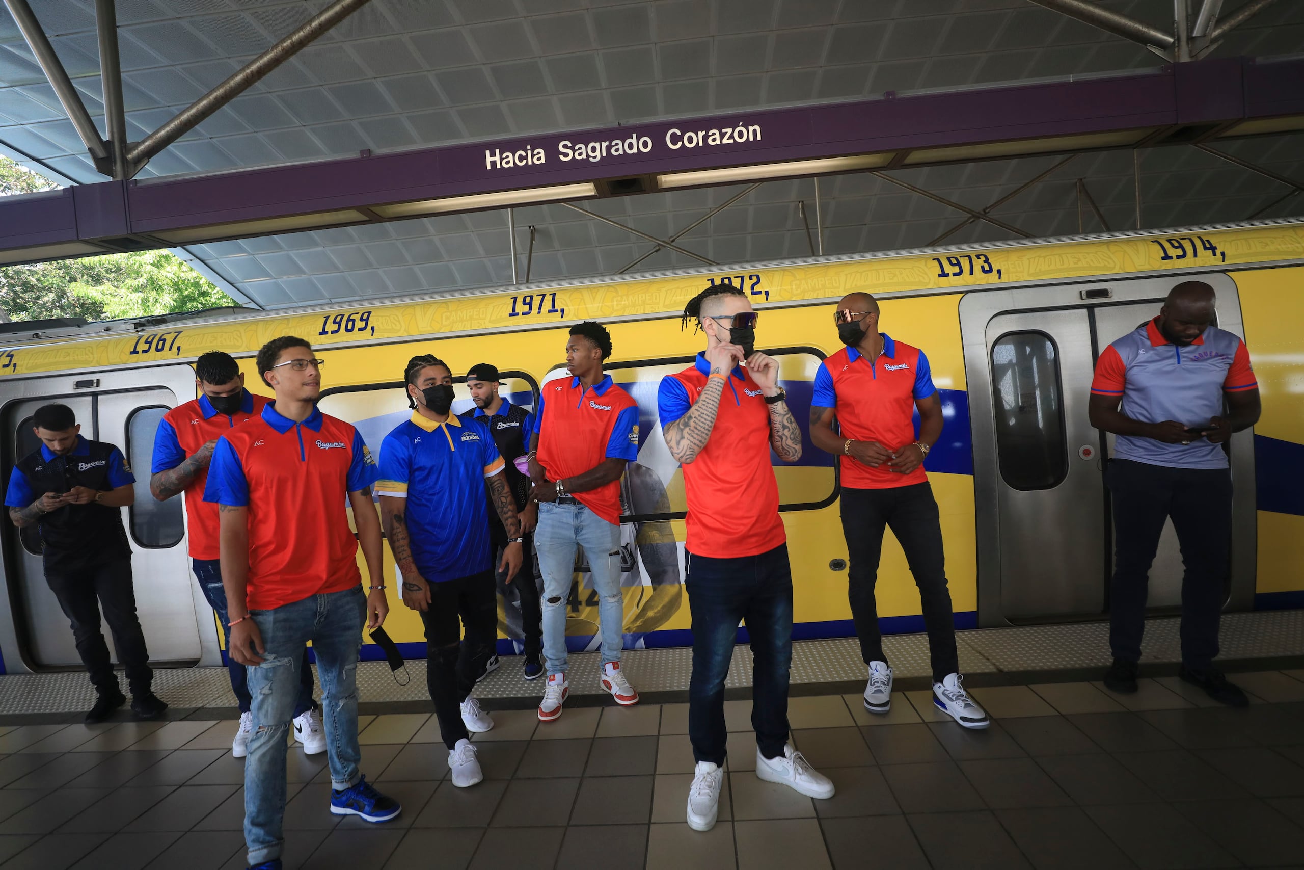 Los integrantes de los Vaqueros de Bayamón posan frente al vagón que llevará los colores del equipo.