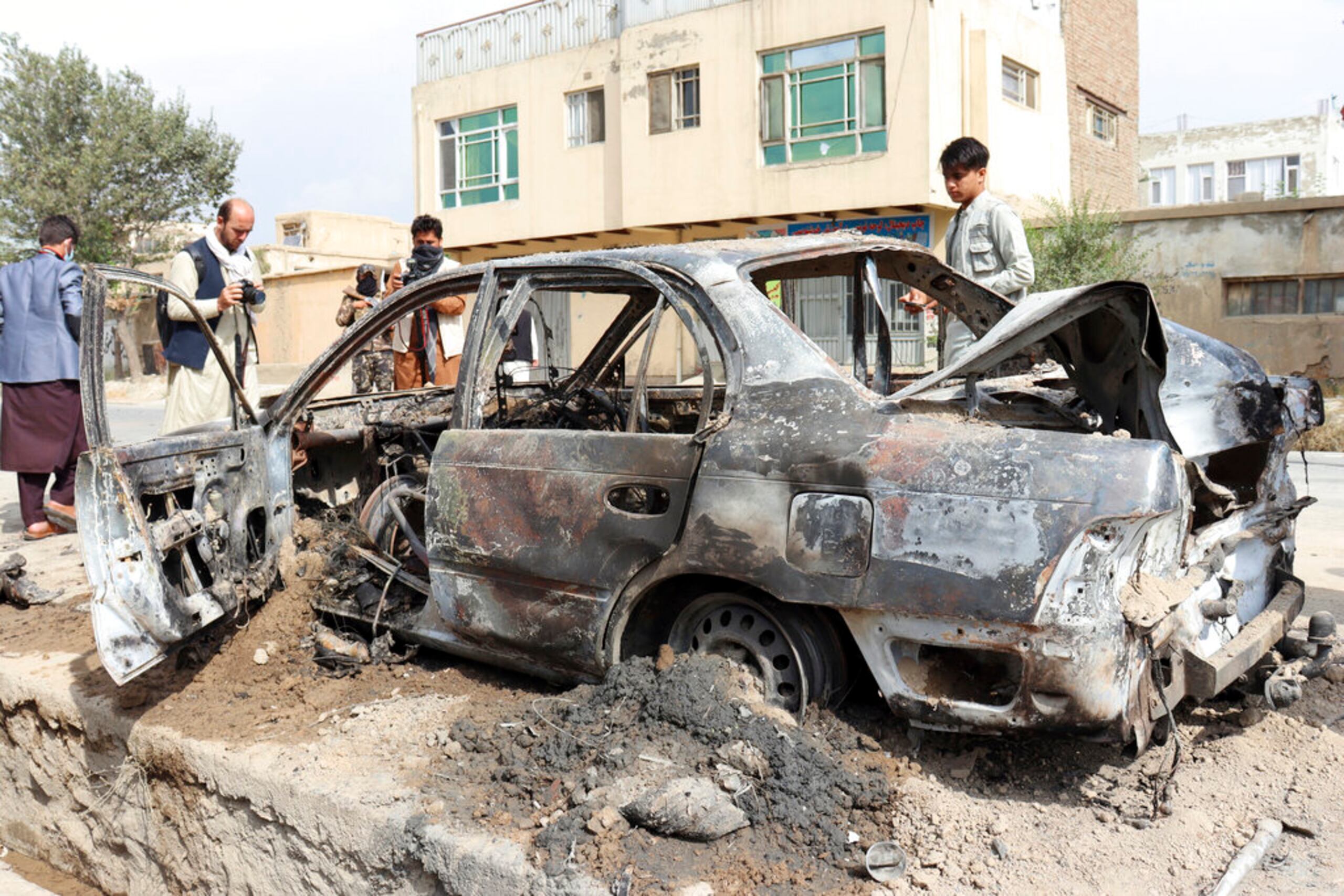 Periodistas toman fotos de un vehículo dañado por un ataque con cohetes en Kabul, Afganistán, el 30 de agosto de 2021.