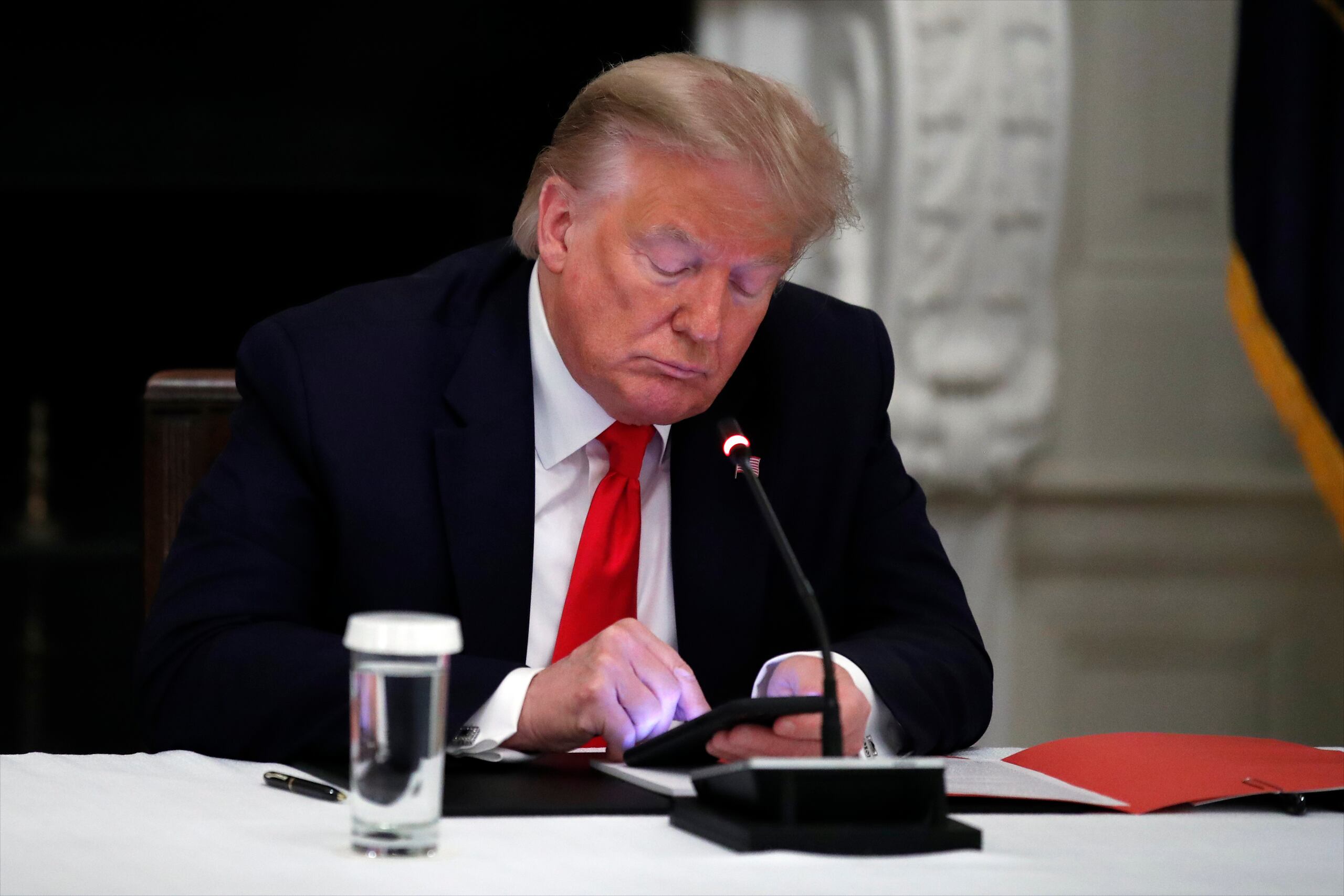 Fotografía de archivo del 18 de junio de 2020 del presidente Donald Trump usando su teléfono durante una reunión con gobernadores en la Casa Blanca, en Washington.