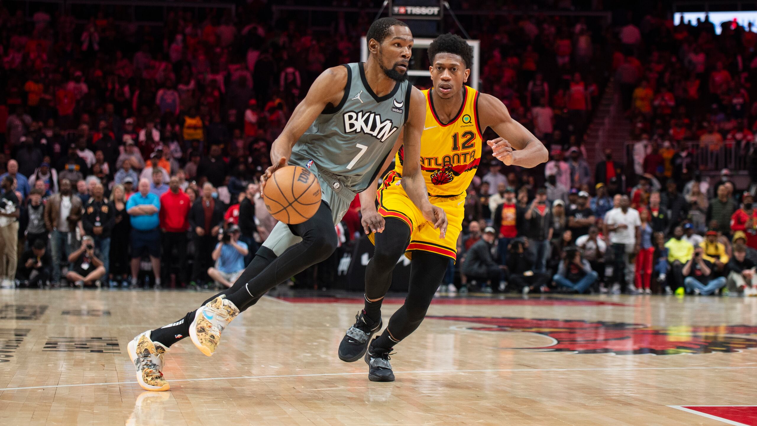 Brooklyn Nets forward Kevin Durant (7) dribbles past Atlanta Hawks forward De'Andre Hunter (12) during the second half of an NBA basketball game Saturday, April 2, 2022, in Atlanta. (AP Photo/Hakim Wright Sr.)