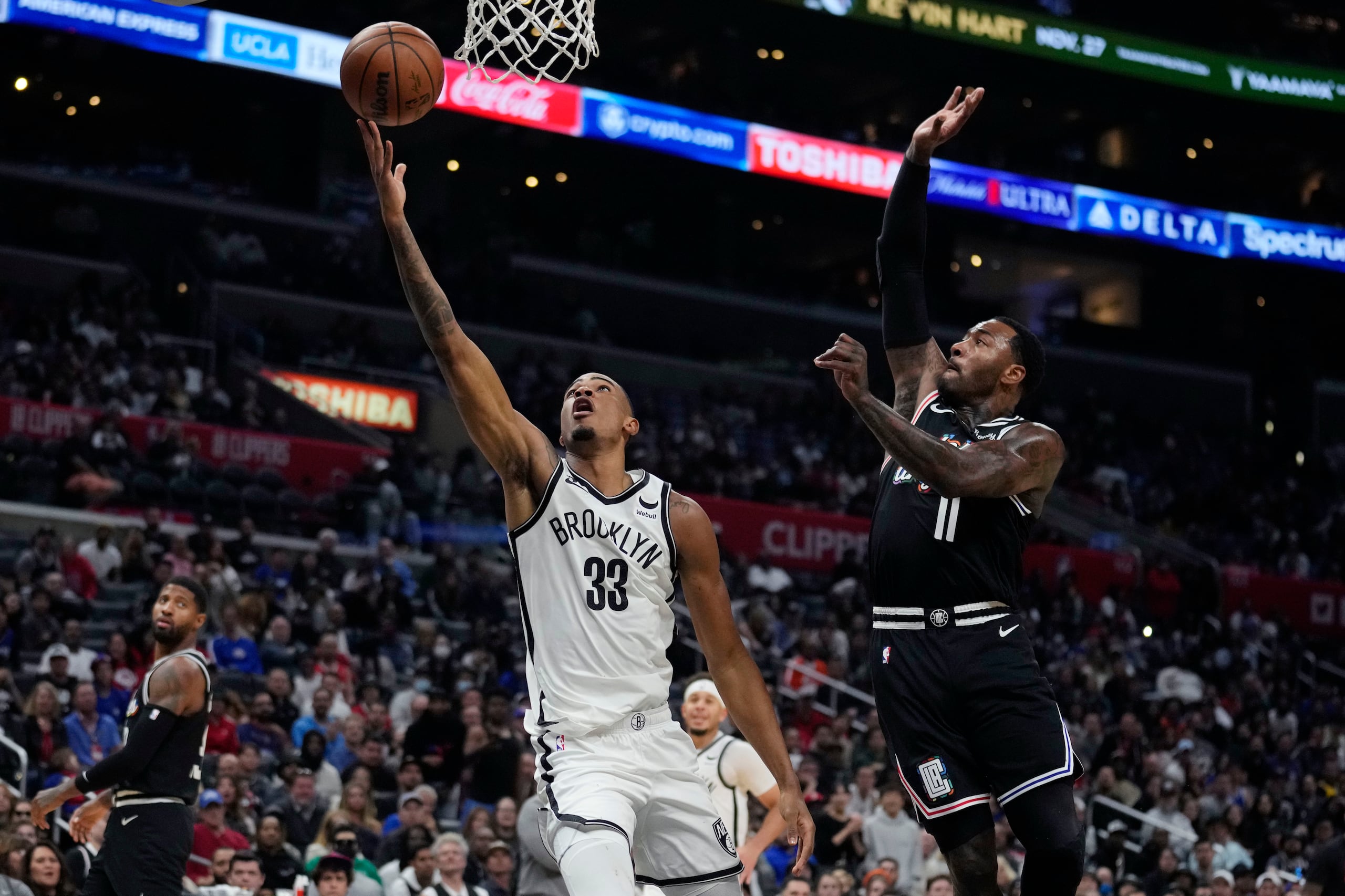 Nic Claxton, alero de los Nets de Brooklyn, anota frente a John Wall, base de los Clippers de Los Ángeles.