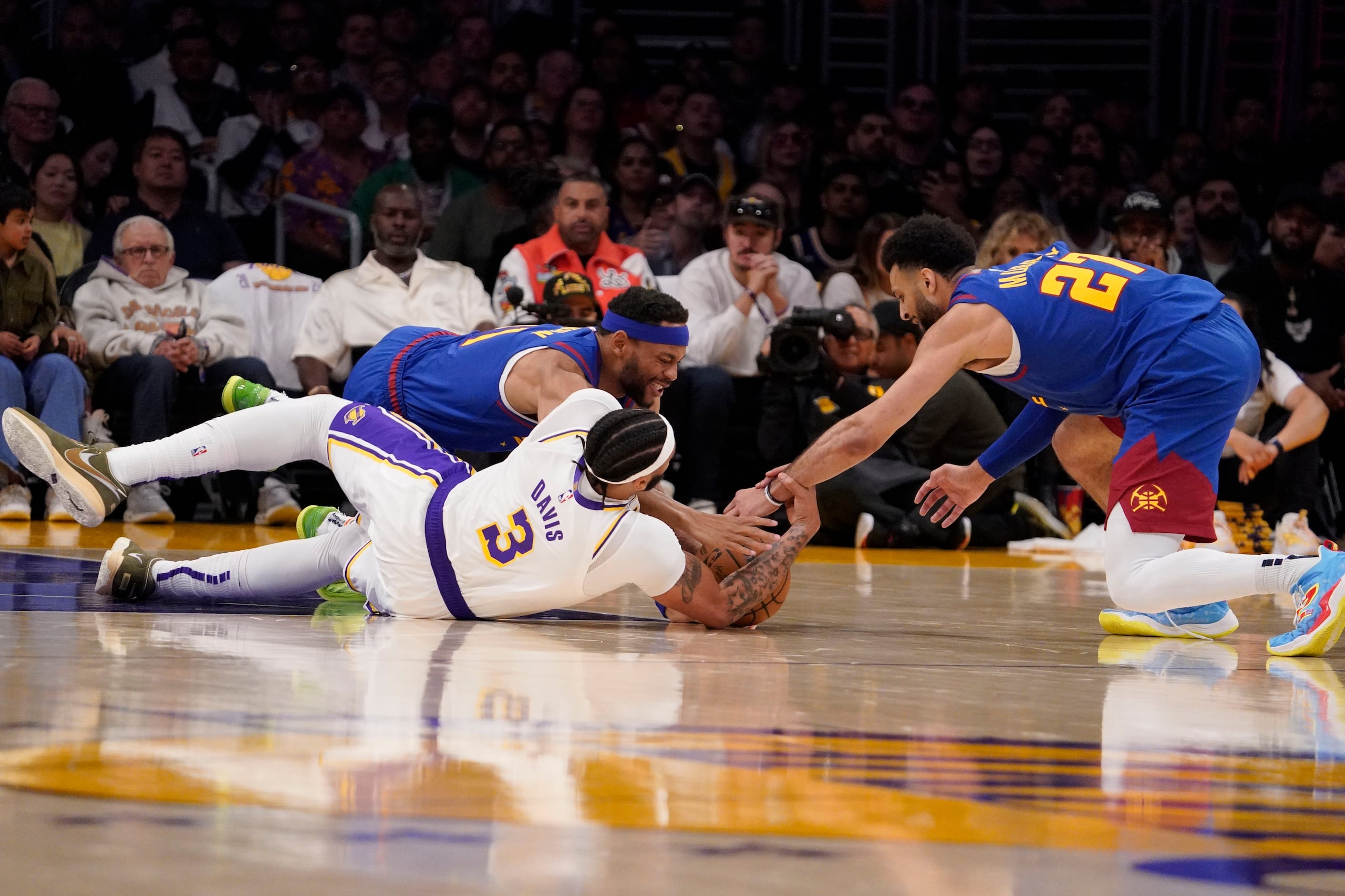 Bruce Brown, a la izquierda, y Jamal Murray (27) se tiran al suelo luchando un balón con el delantero de los Lakers, Anthony Davis.