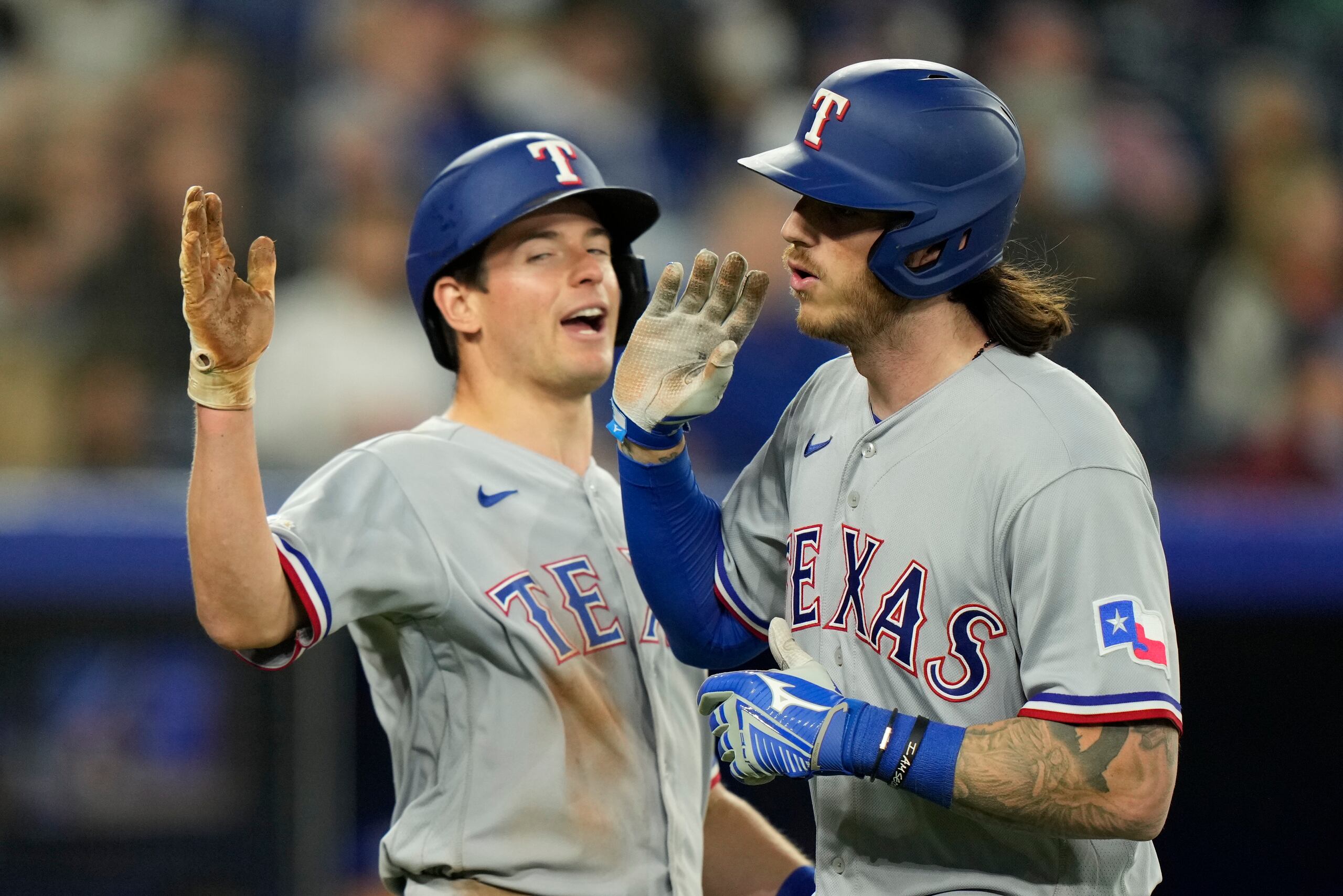 Jonah Heim (derecha) de los Rangers de Texas recibe el saludo de su compañero Brad Miller tras el jonrón de Heim ante los Azulejos de Toronto, el domingo 10 de abril de 2022. (Frank Gunn/The Canadian Press vía AP)