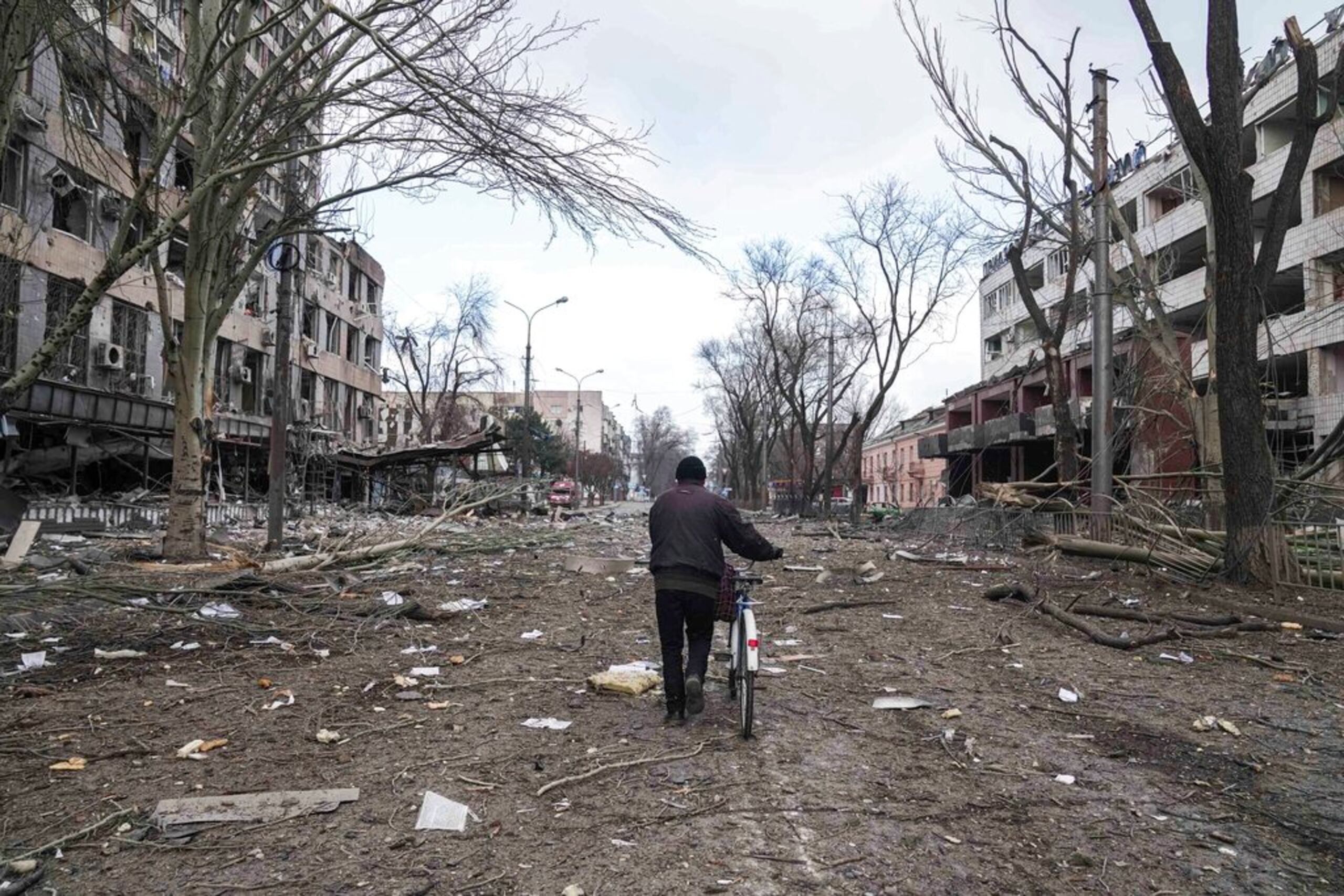 Un hombre camina con una bicicleta en una calle dañada por los bombardeos en Mariúpol, Ucrania, el 10 de marzo de 2022.