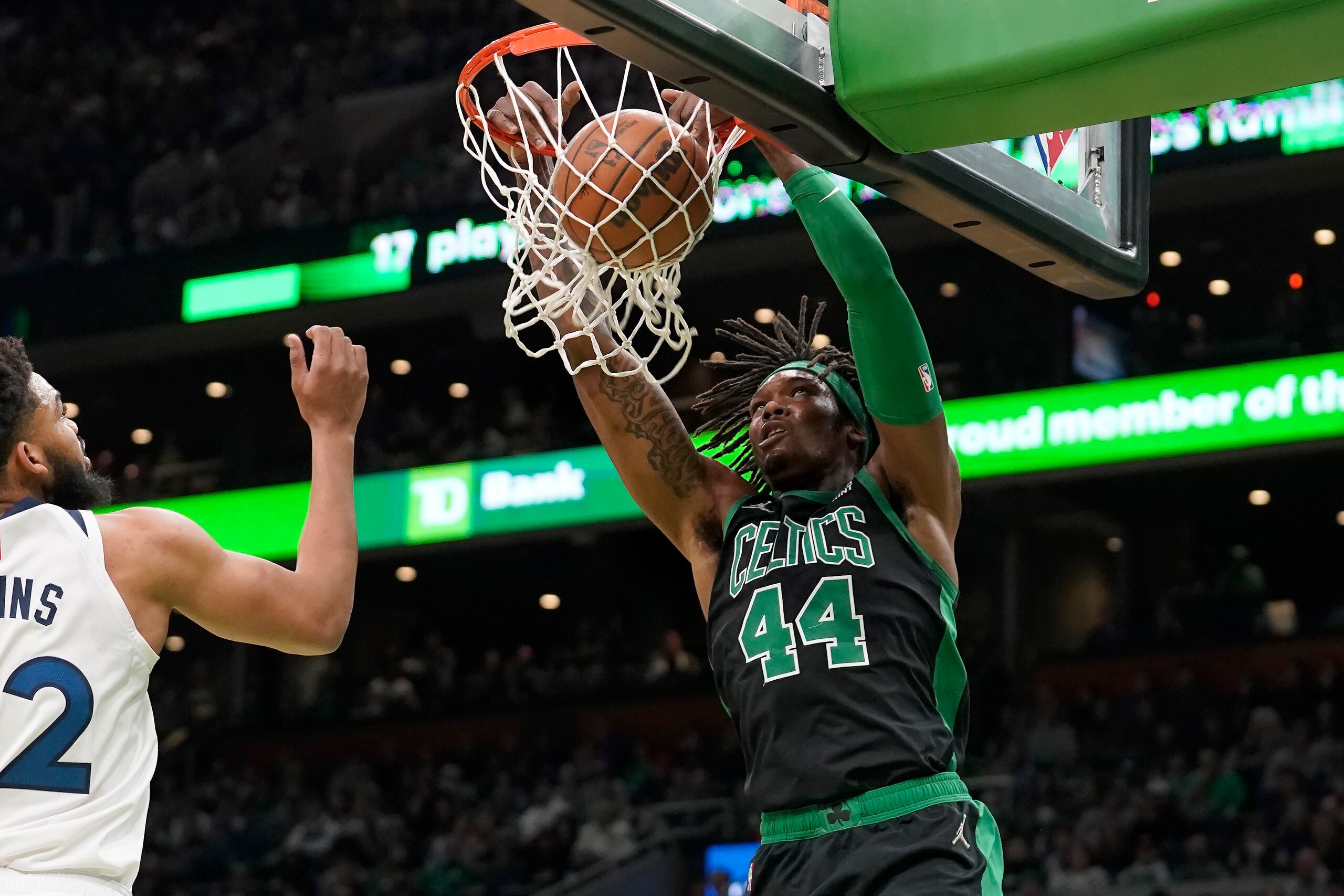 En foto del domingo 27 de marzo del 2022, Robert Williams III (44), de los Celtics de Boston, consigue una volcada frente a Karl-Anthony Towns (32), de los Timberwolves de Minnesota, en la primera mitad del partido de la NBA en Boston. El lunes 28 de marzo del 2022, los Celtics confirman que Williams sufrió un desgarre en el menisco en el encuentro del domingo.  (AP Foto/Steven Senne)