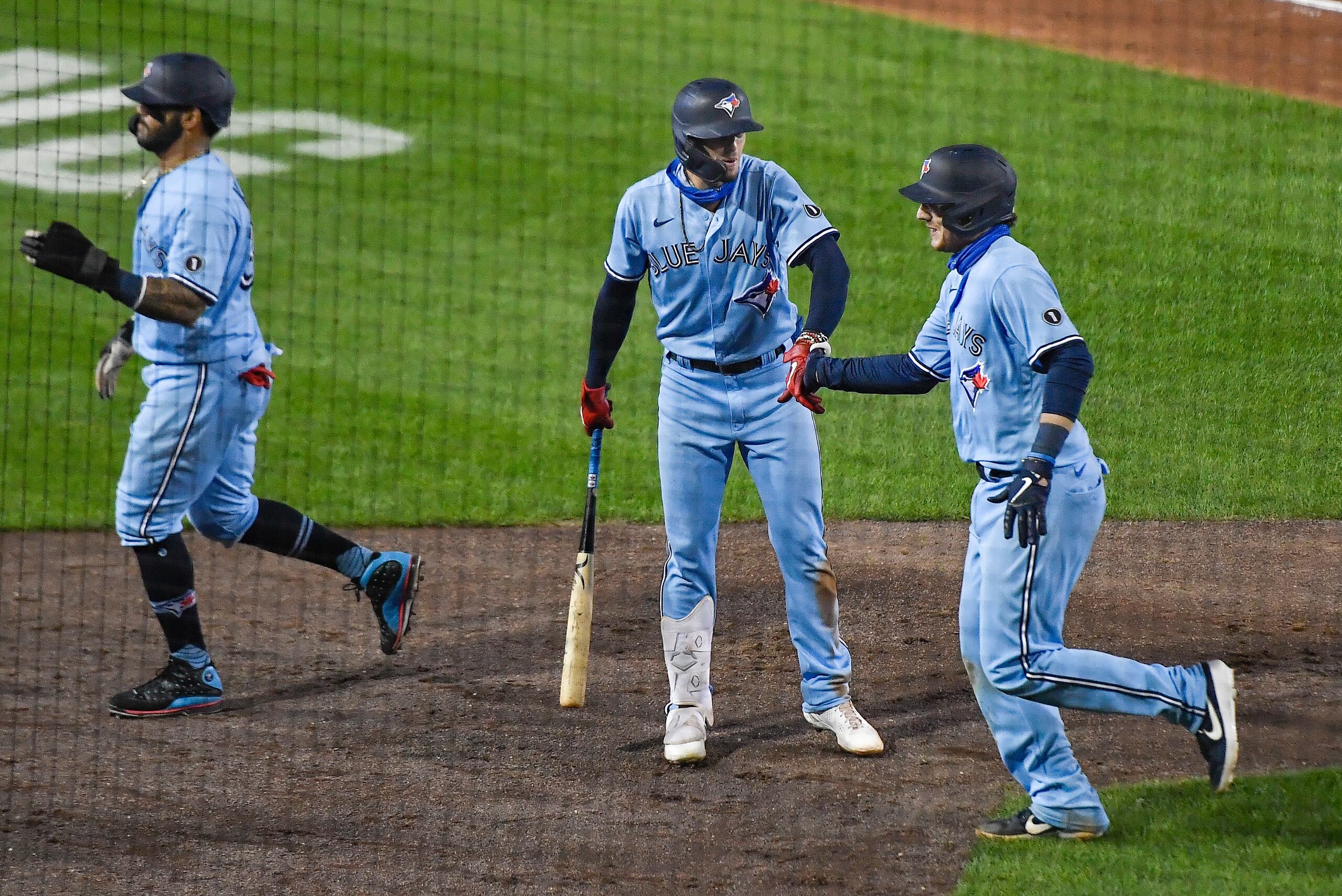 Danny Jansen, de los Azulejos de Toronto,  a la derecha, recibe la felicitación de Cavan Biggio luego de pegar un 'grand slam' en la sexta entrada del juego.